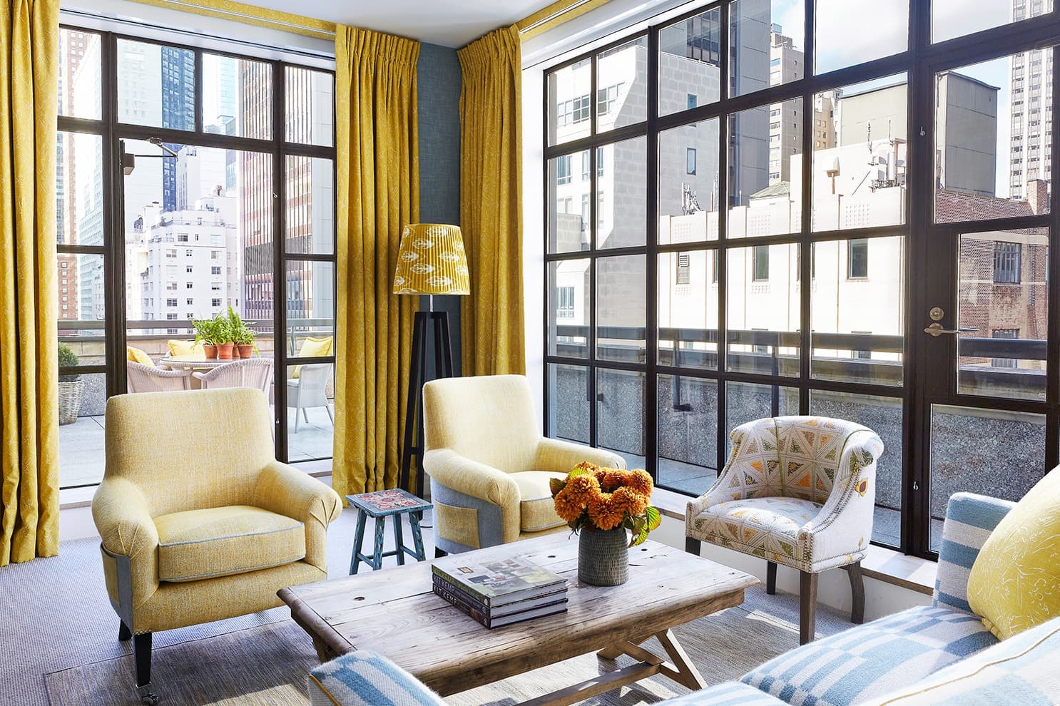 a sunlit living room with giant windows and plush yellow chairs