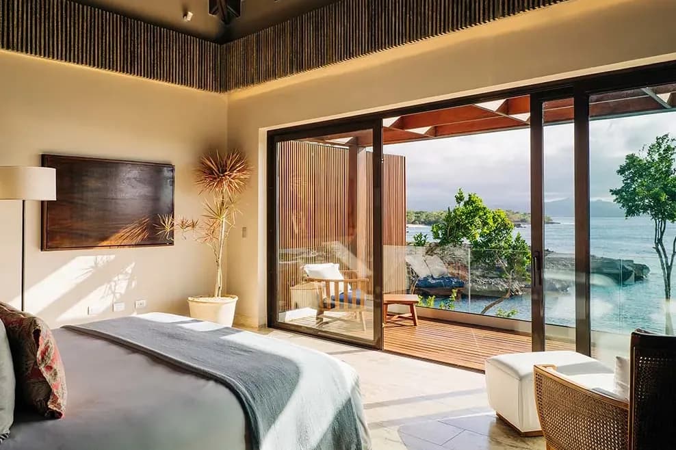 a luxurious hotel bedroom with a terrace overlooking the ocean