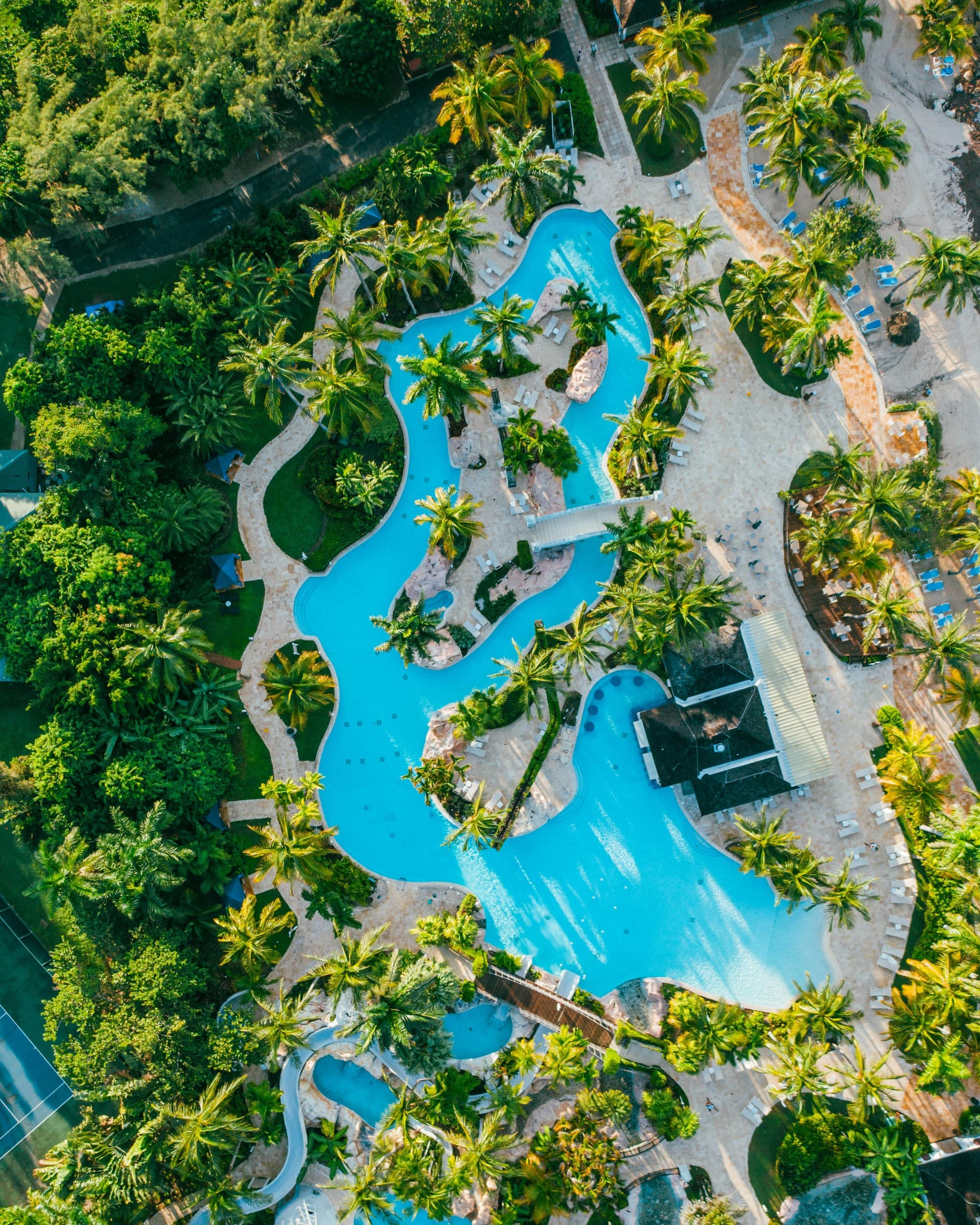 Aerial view of resort with trees and pools.