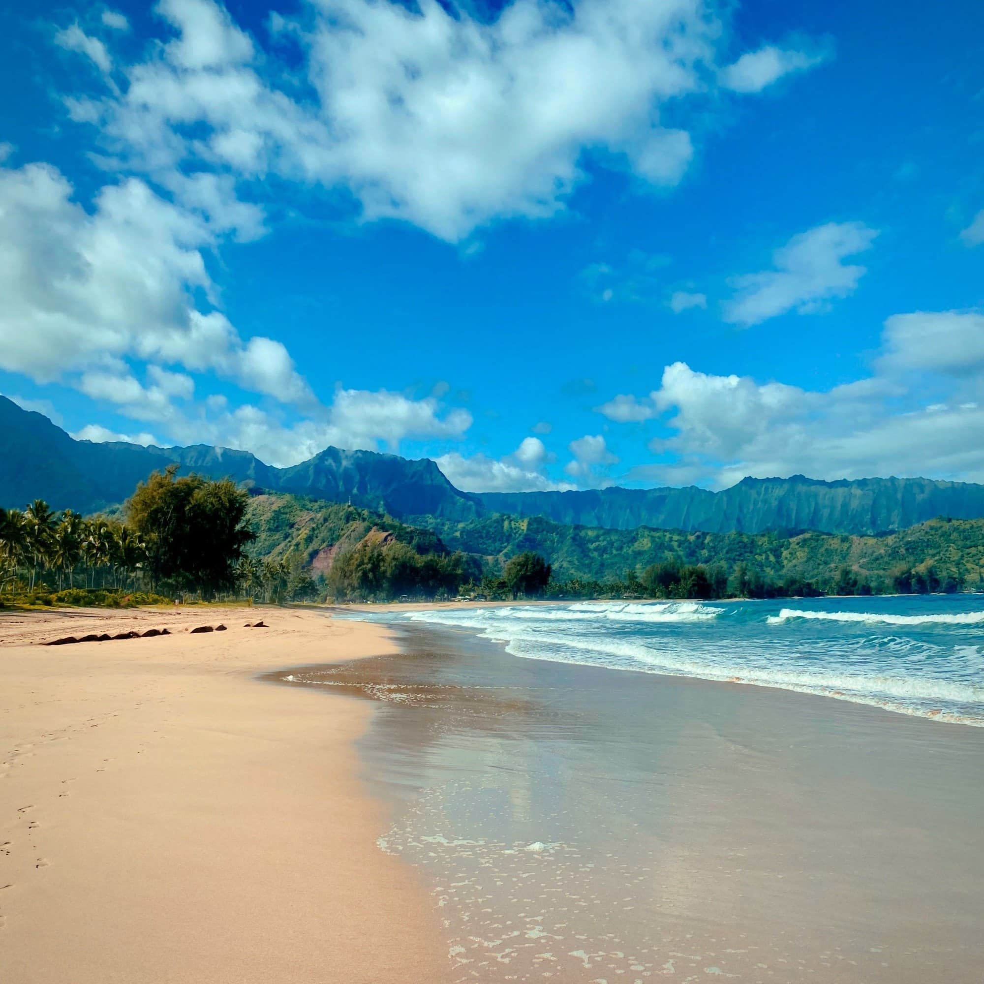 A serene beach setting with clear skies, gentle waves, and distant mountains, evoking tranquility.