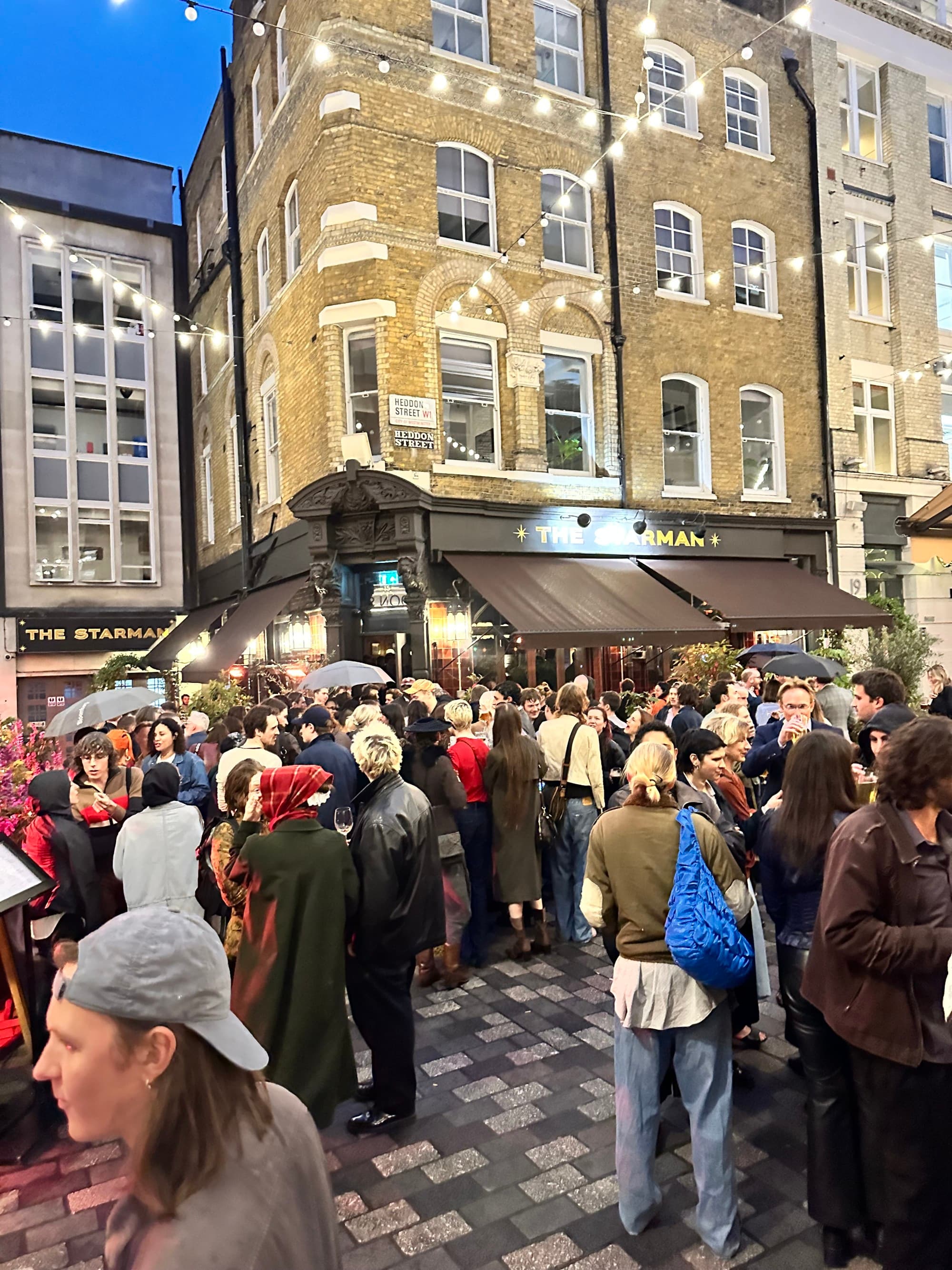 A courtyard with crowds standing outside of The Starman bar.