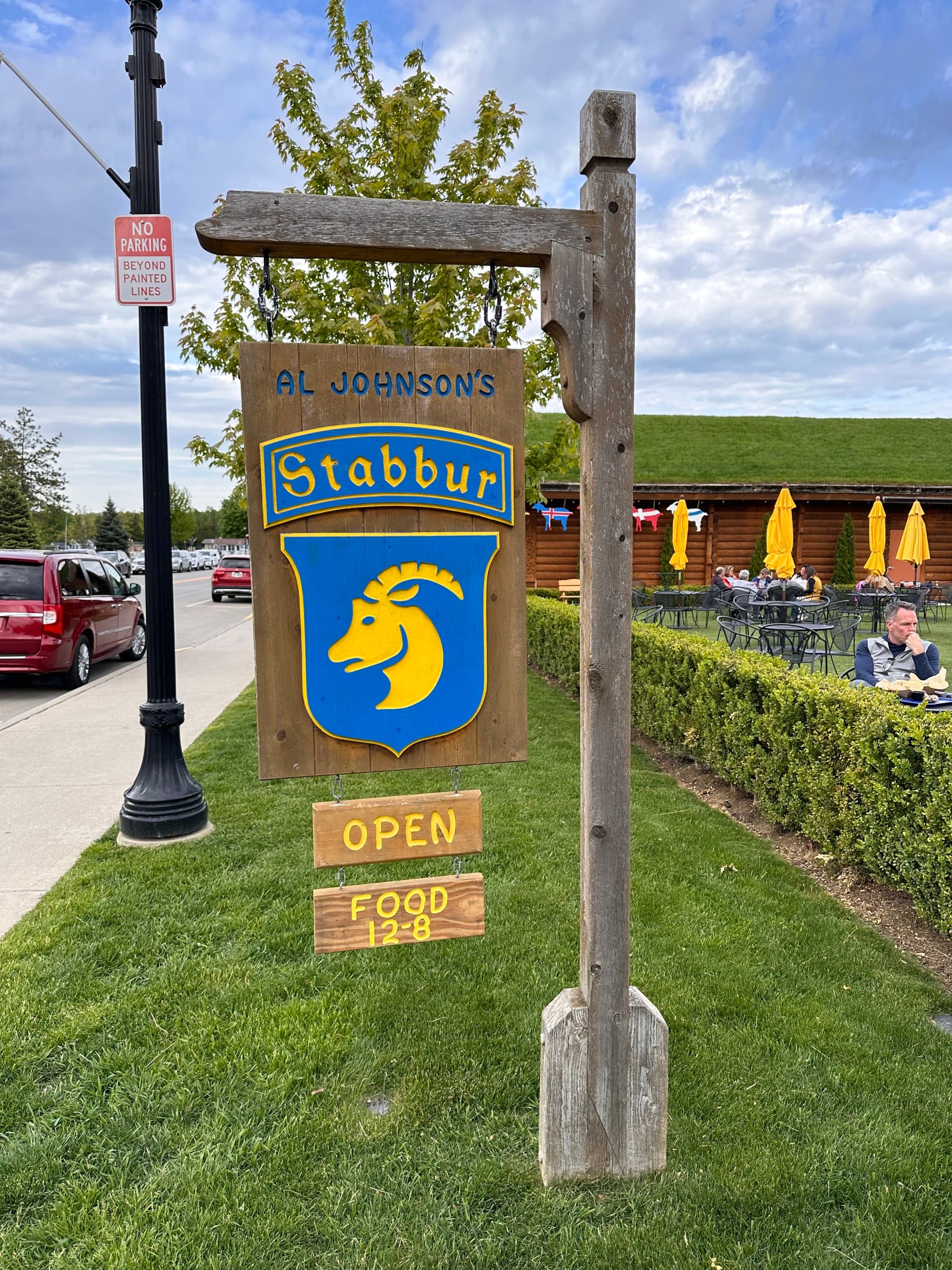 The image portrays a vibrant outdoor sign for “Al Johnson’s Swedish Restaurant & Butik,” featuring a blue and yellow logo with a stylized goat, indicating the cultural theme and unique appeal of the establishment.