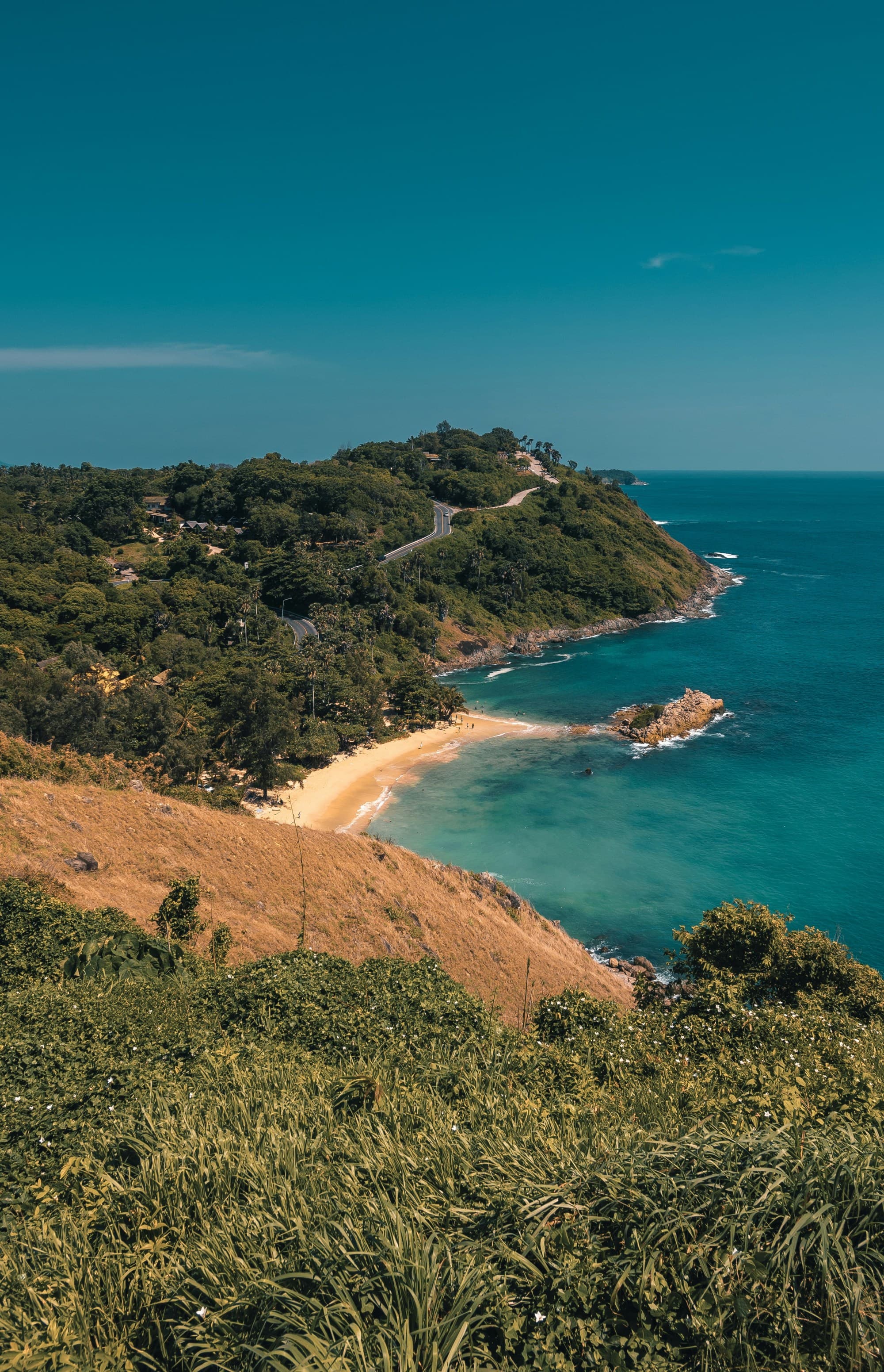 A peninsula on an island covered in greenery, jutting out into turquoise blue water.