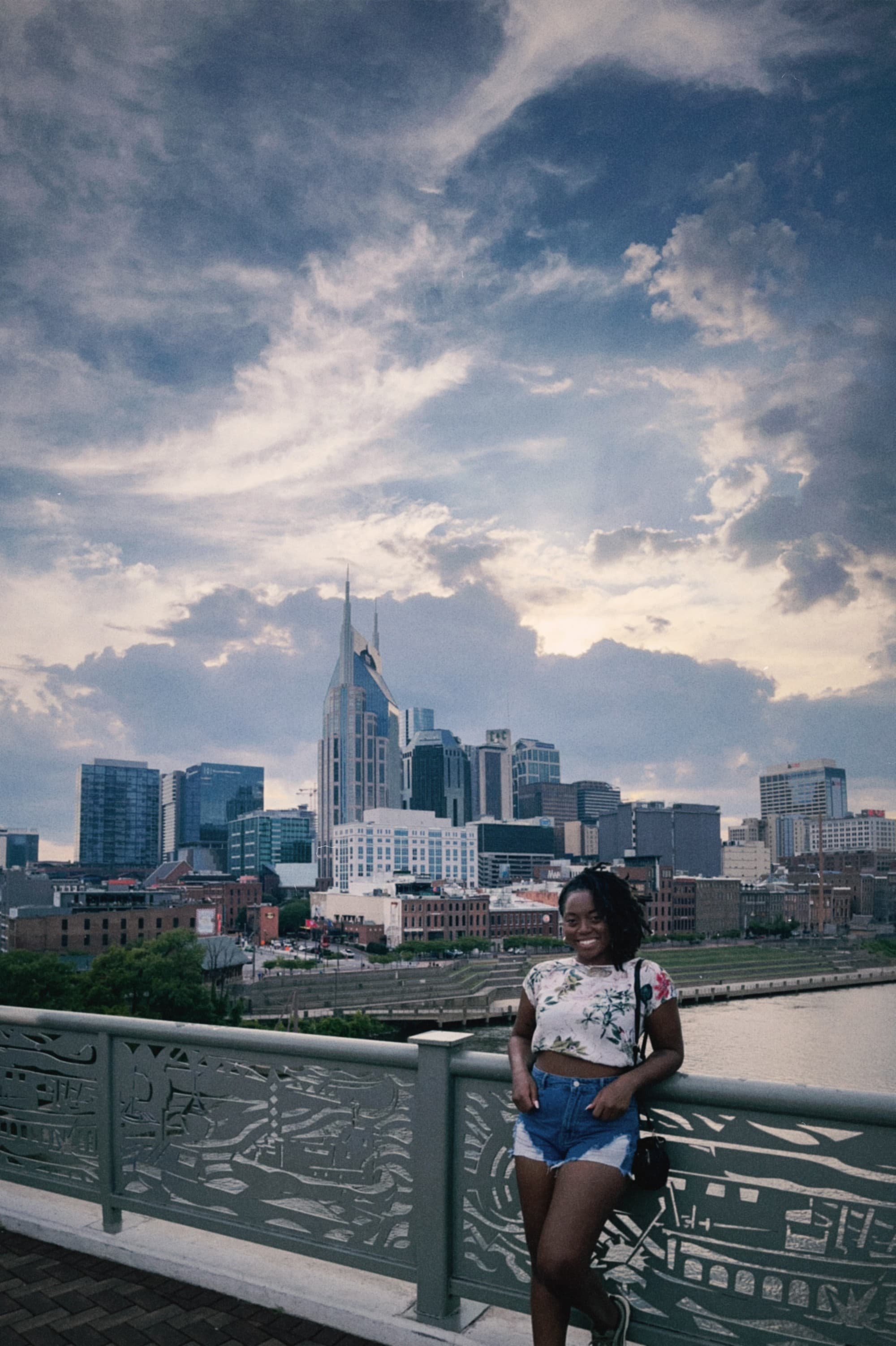 Advisor posing for a photo against a railing on a bridge with a city skyline in the background