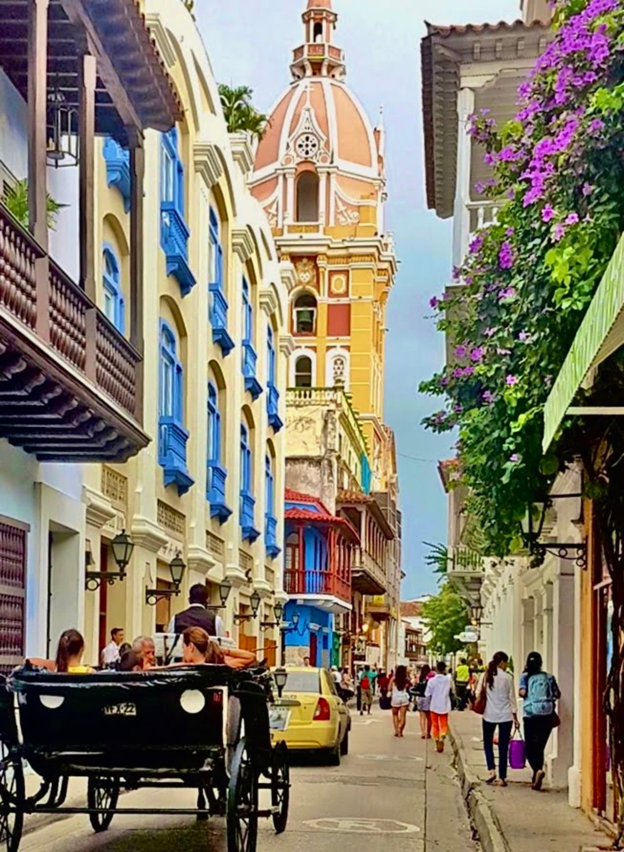 A picturesque street in Cartagena de Indias, Colombia, bustling with life and colonial charm under a bright sky.