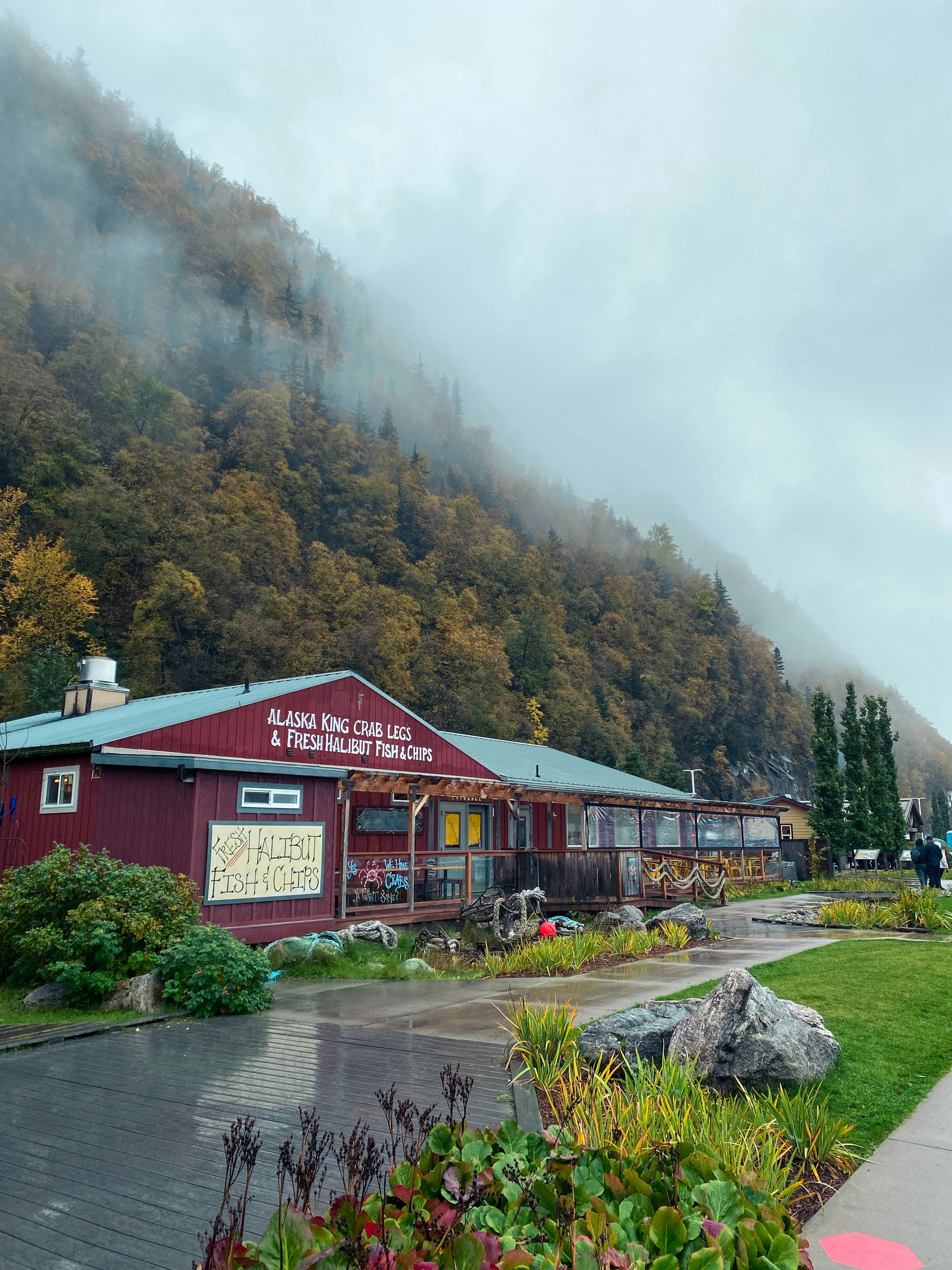 A red building that says "Alaska king crab legs" sitting next to a lush green hillside