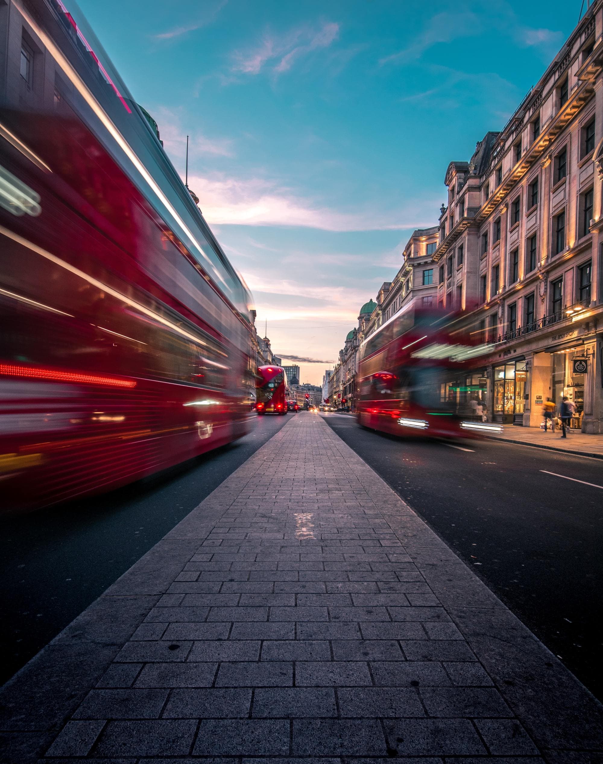 red double decker bus speeds by on either side of the street at sunset