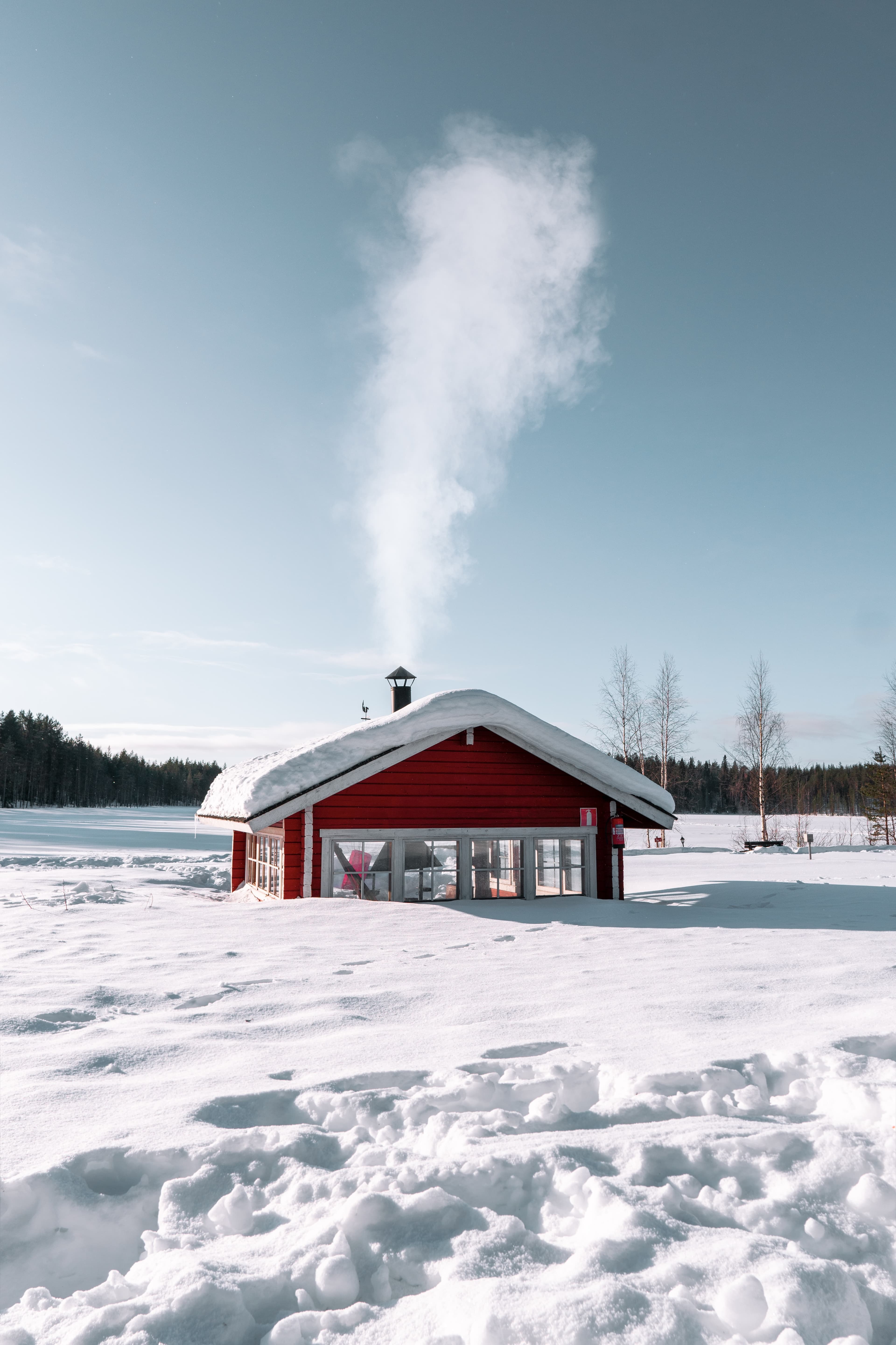 A picture of a red wooden house amongst snow in Finland.