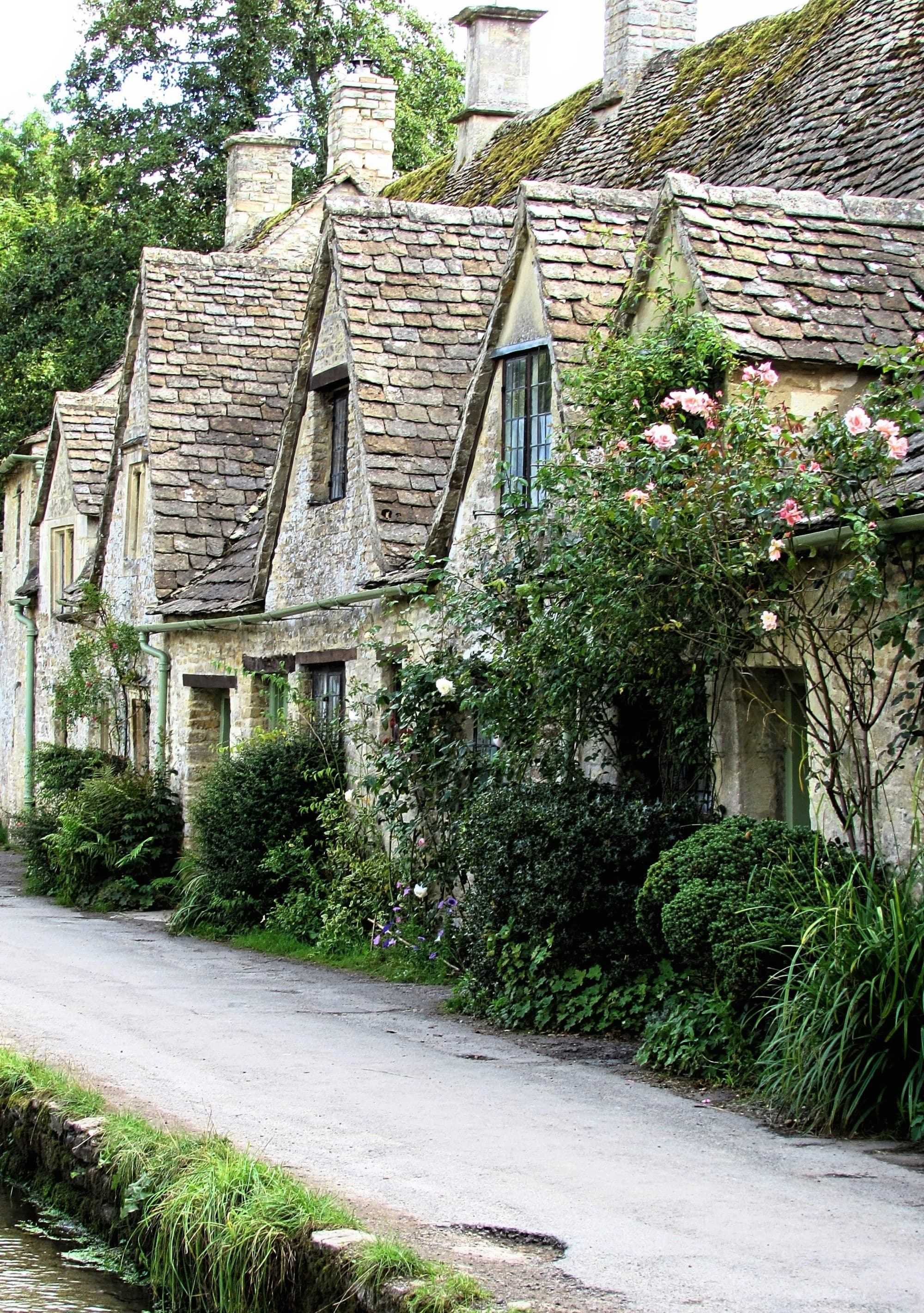 A row of gray stone housse with greeney outside on a picturesque street in England