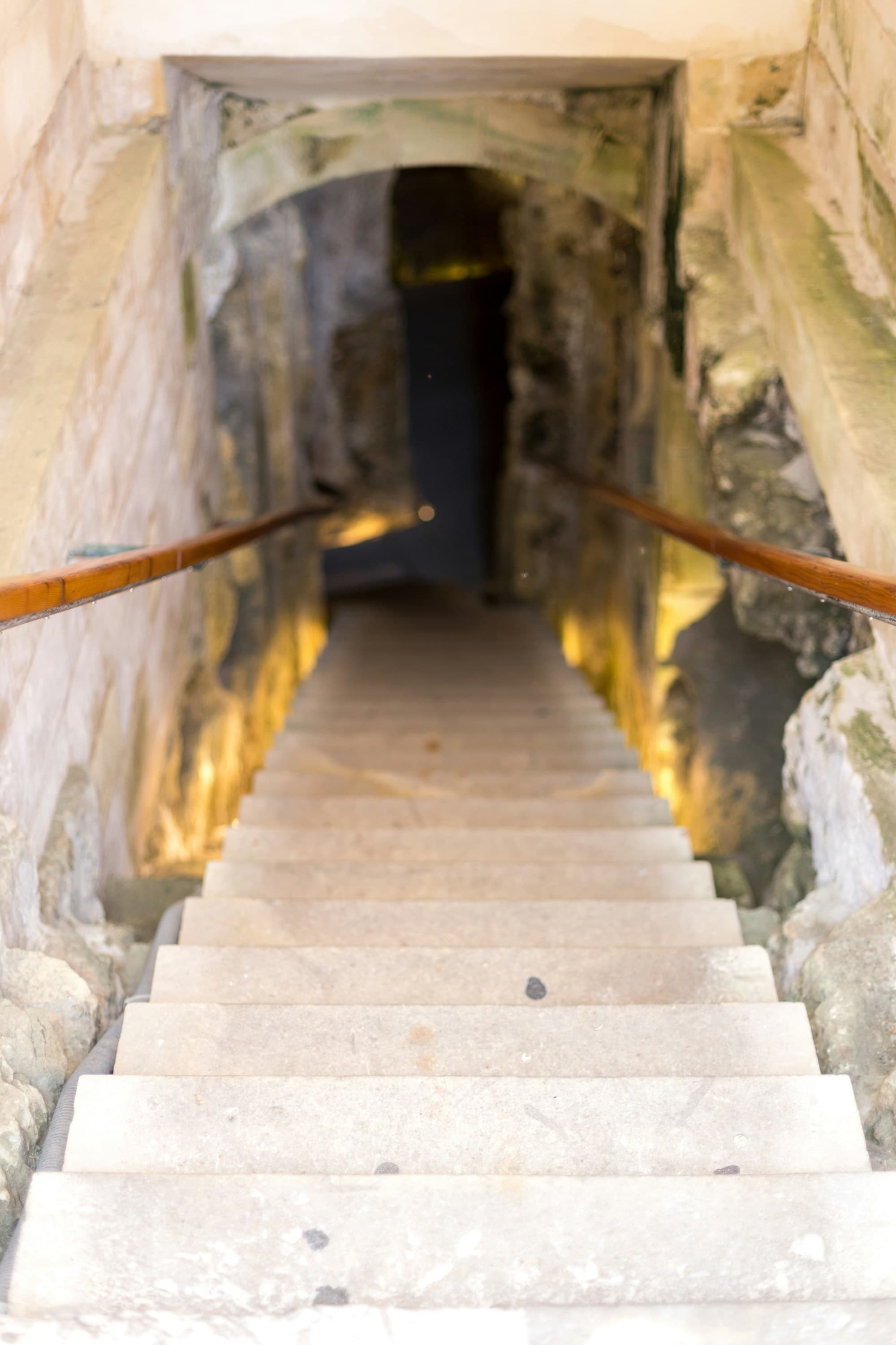 Staircase leading down to underground room with stone walls.