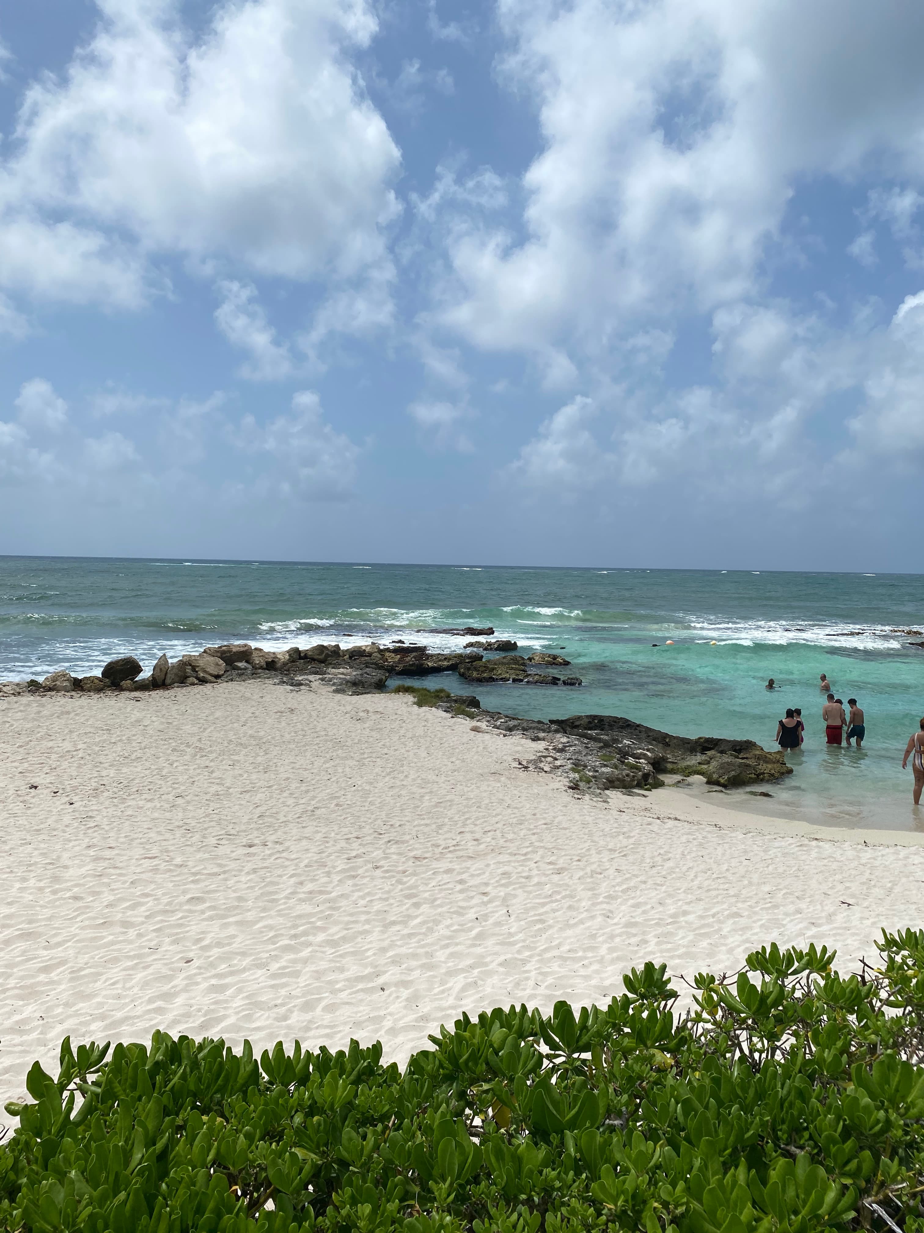 View of the Playa del Carmen beach with people wading in the water during the daytime.