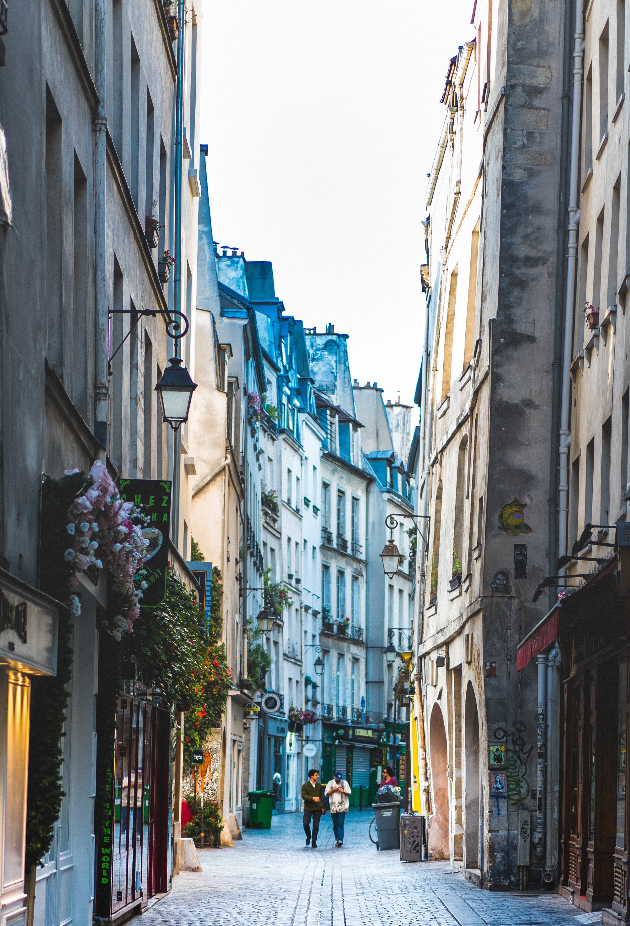 Two people walking down a street in Paris' Le Marais neighborhood.