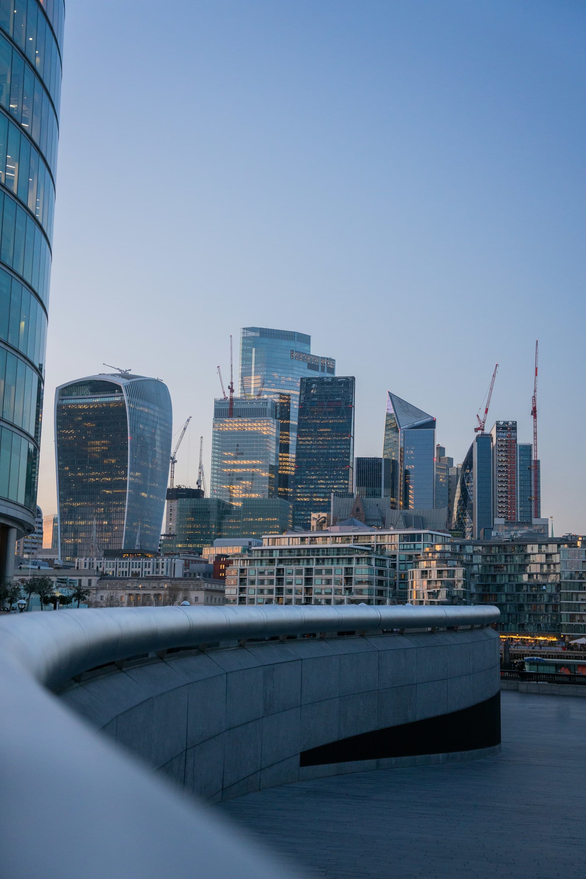 A modern cityscape with snow-covered structures and ongoing construction during a clear, dusk setting.