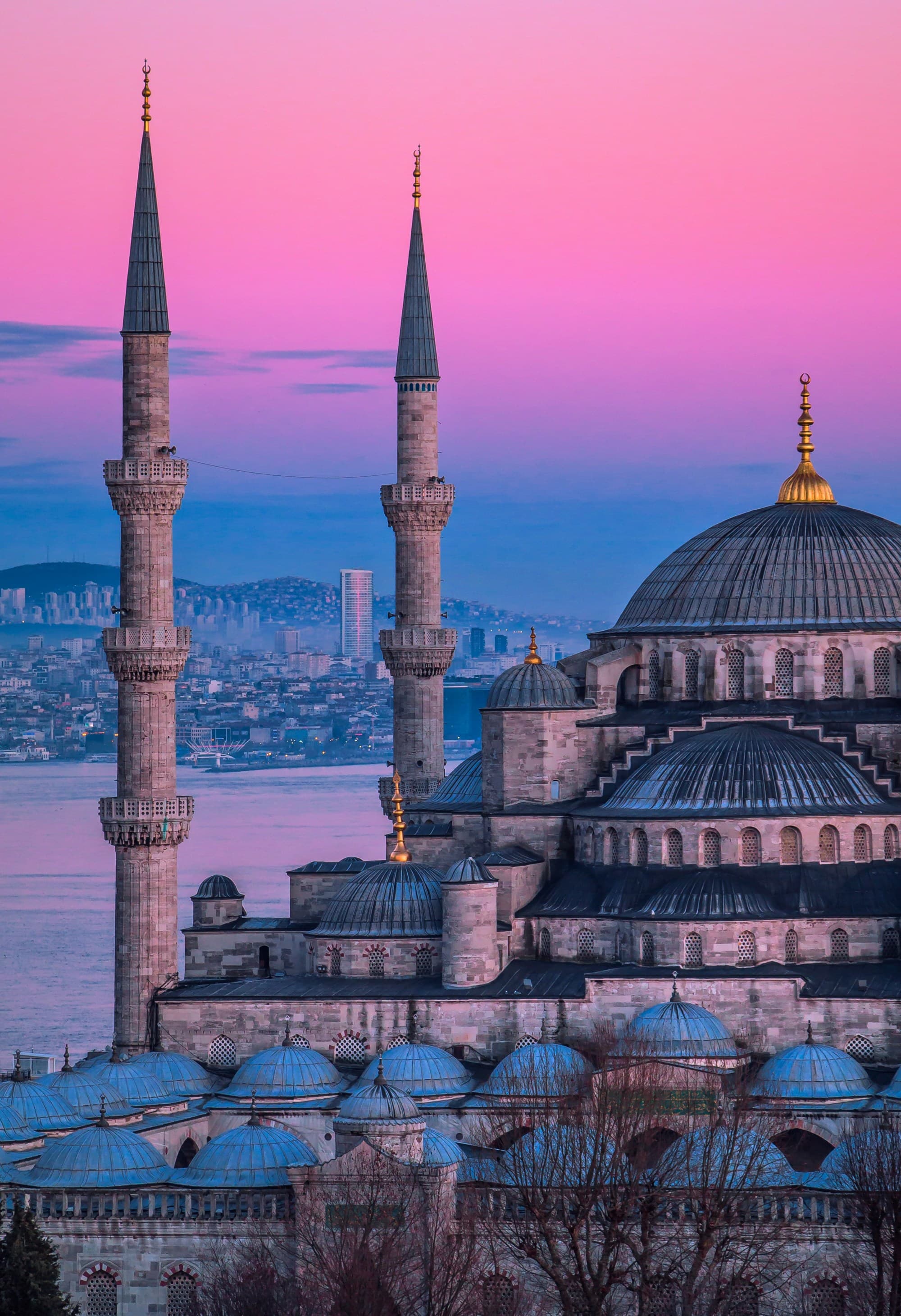 The image captures the serene beauty of the Sultan Ahmed Mosque at sunset, with its minarets and domes silhouetted against a pink sky.