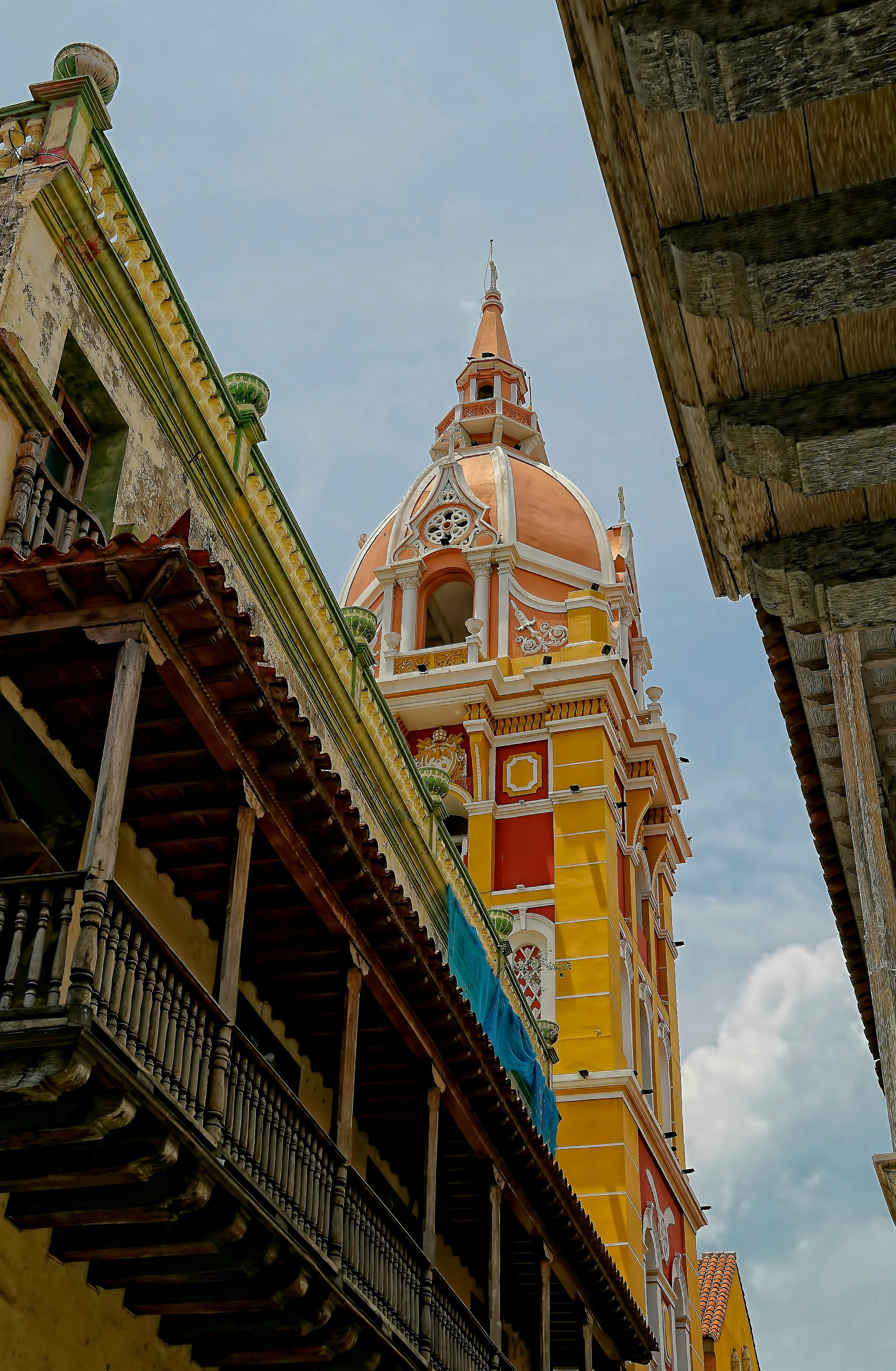 A yellow cathedral as seen from between colorful city streets.