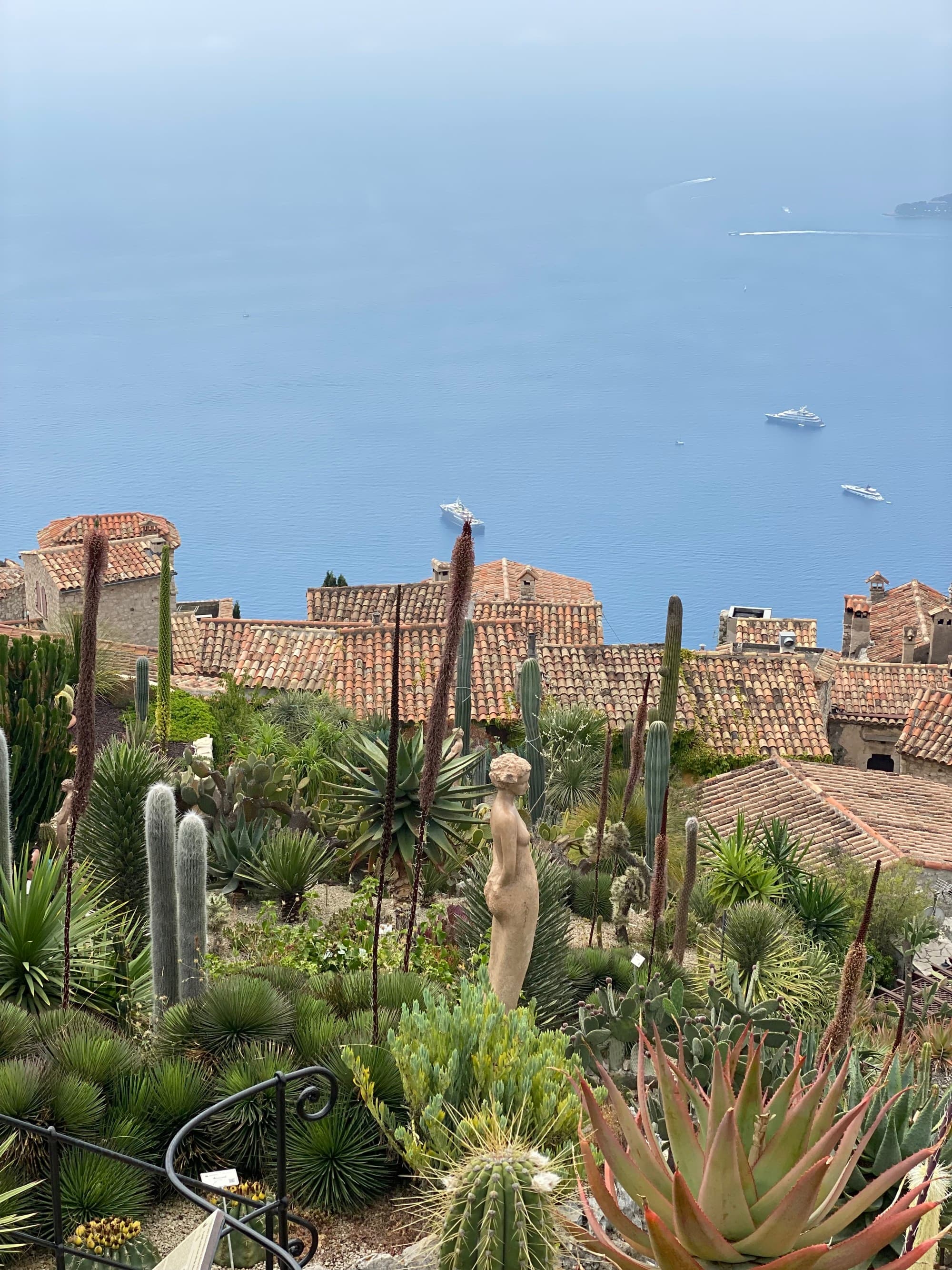 A view of a hillside with a garden and quaint overlooking the ocean.