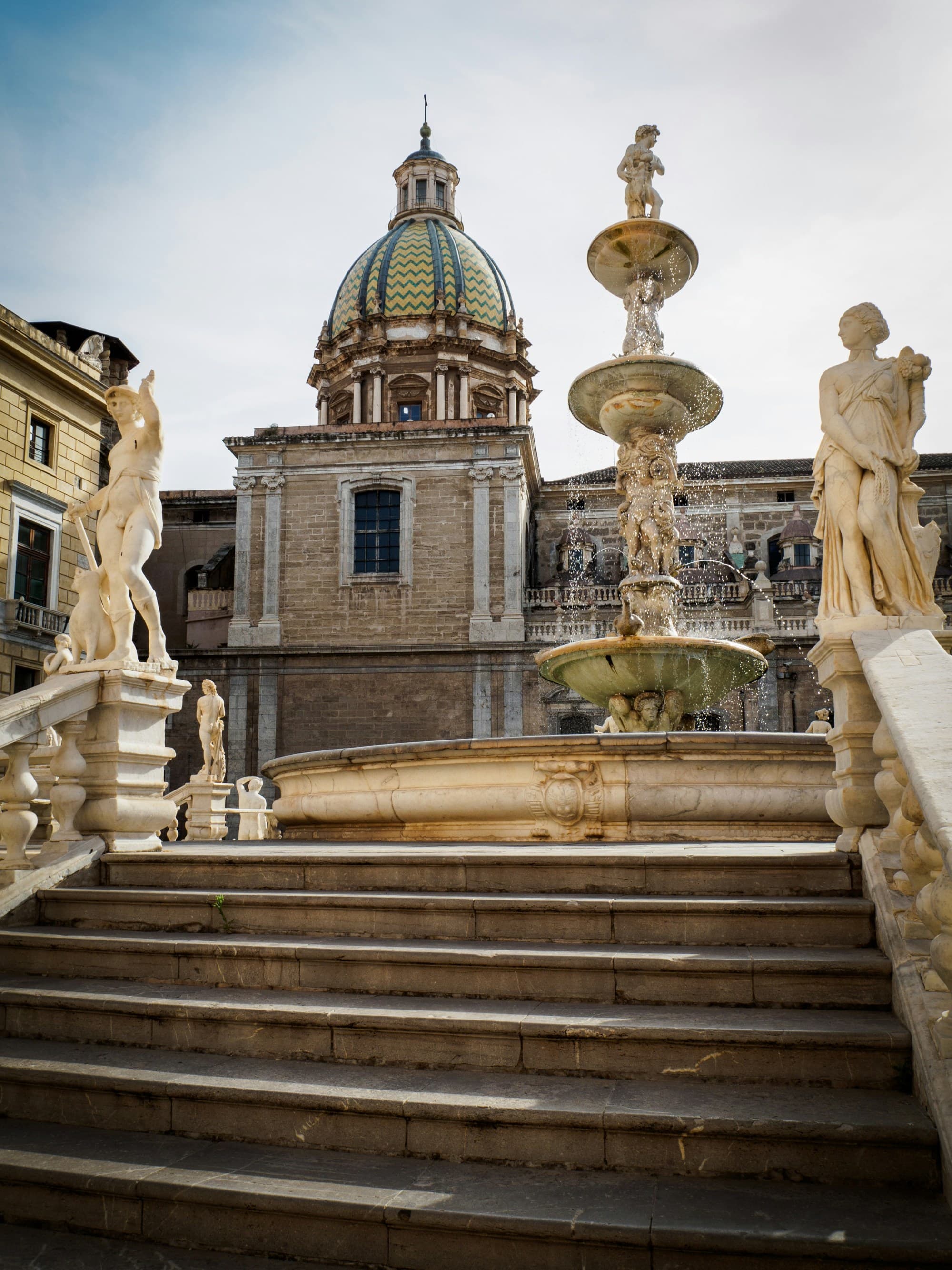 A beautiful architectural scene with a fountain, statues, and a domed building.