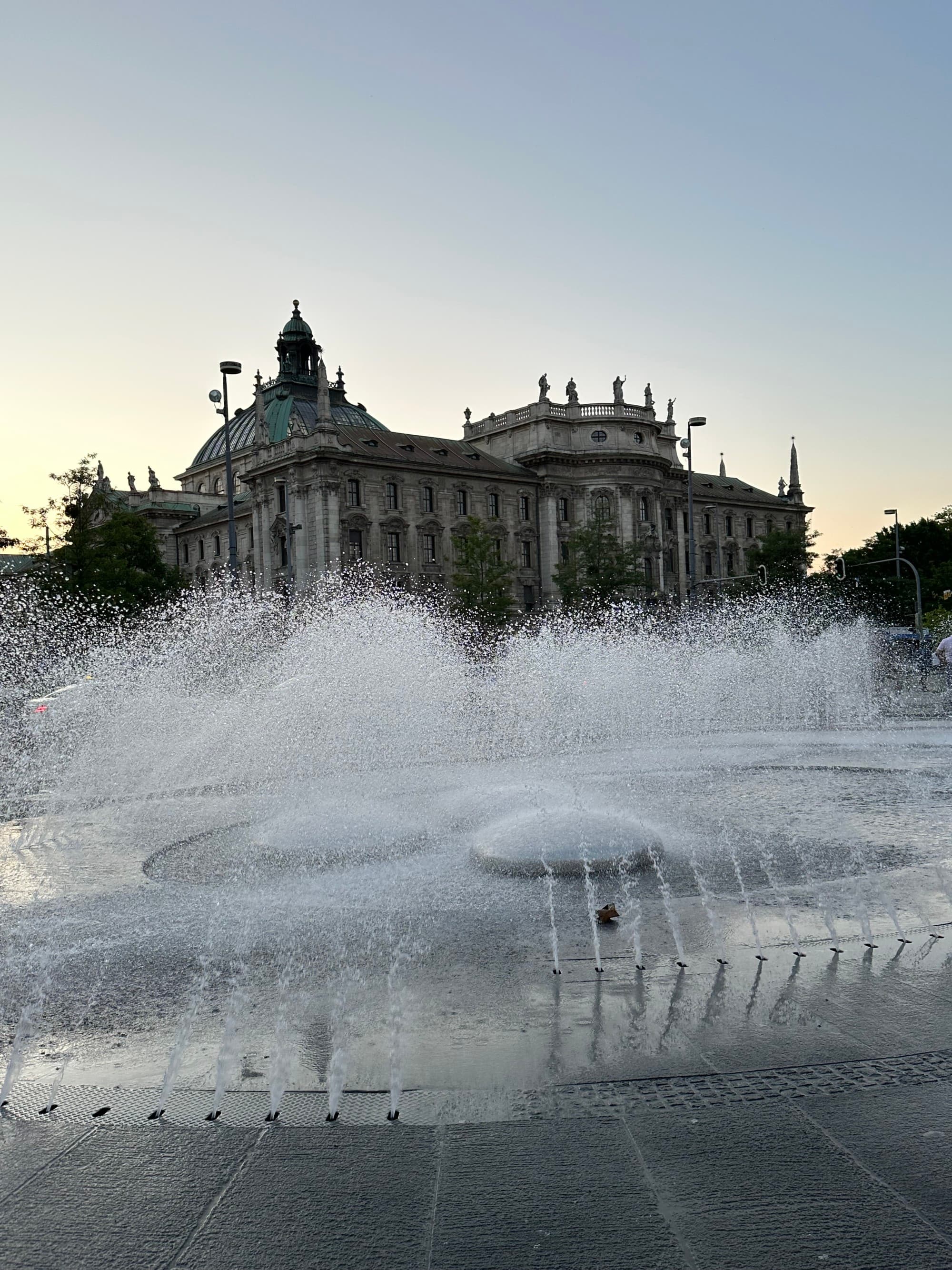 A large fountain in front of an old stone building in Munich, Germany.