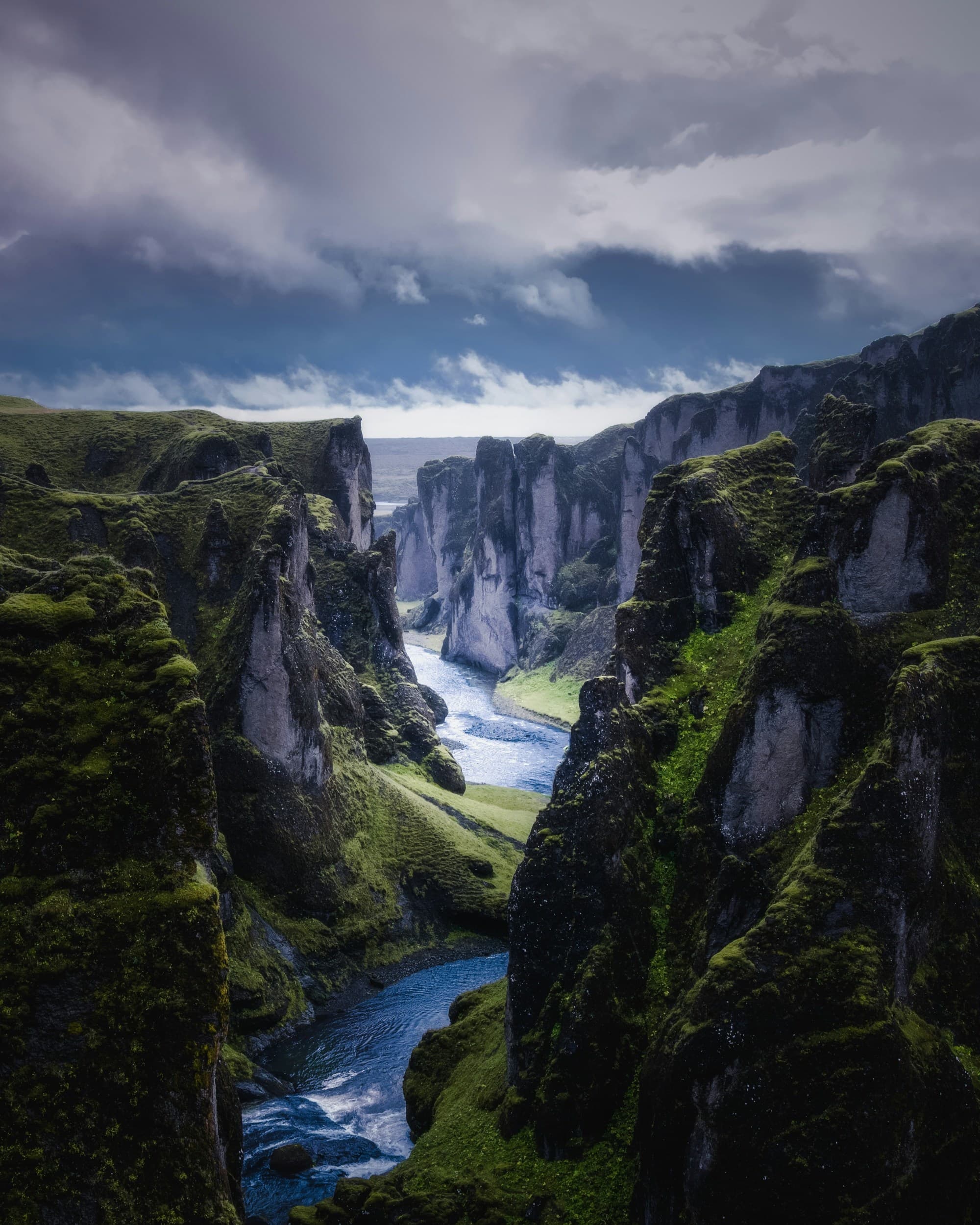 A view of a valley stream between green mountainsides