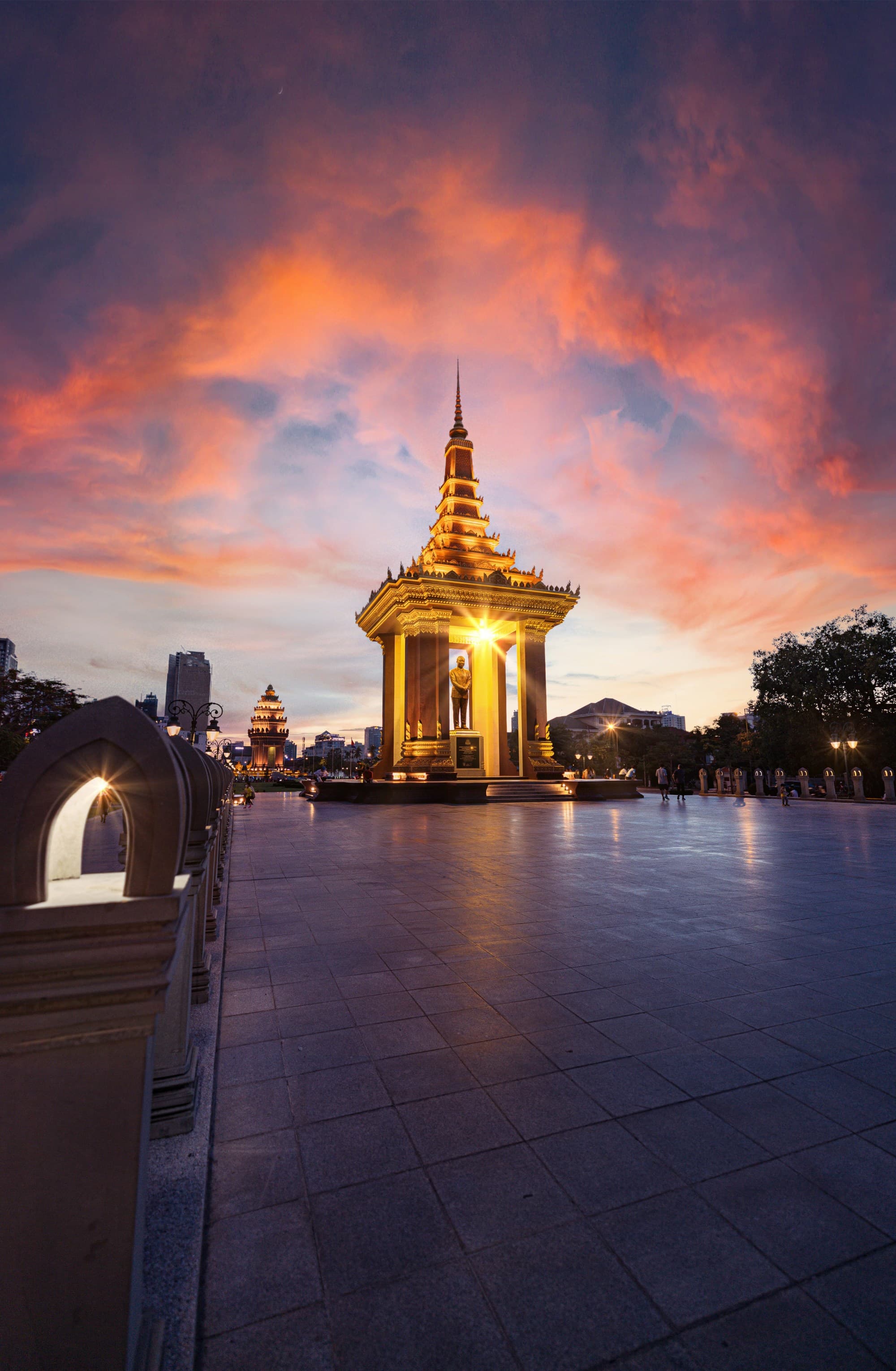 A golden temple lit up at night against a pink and blue sunset