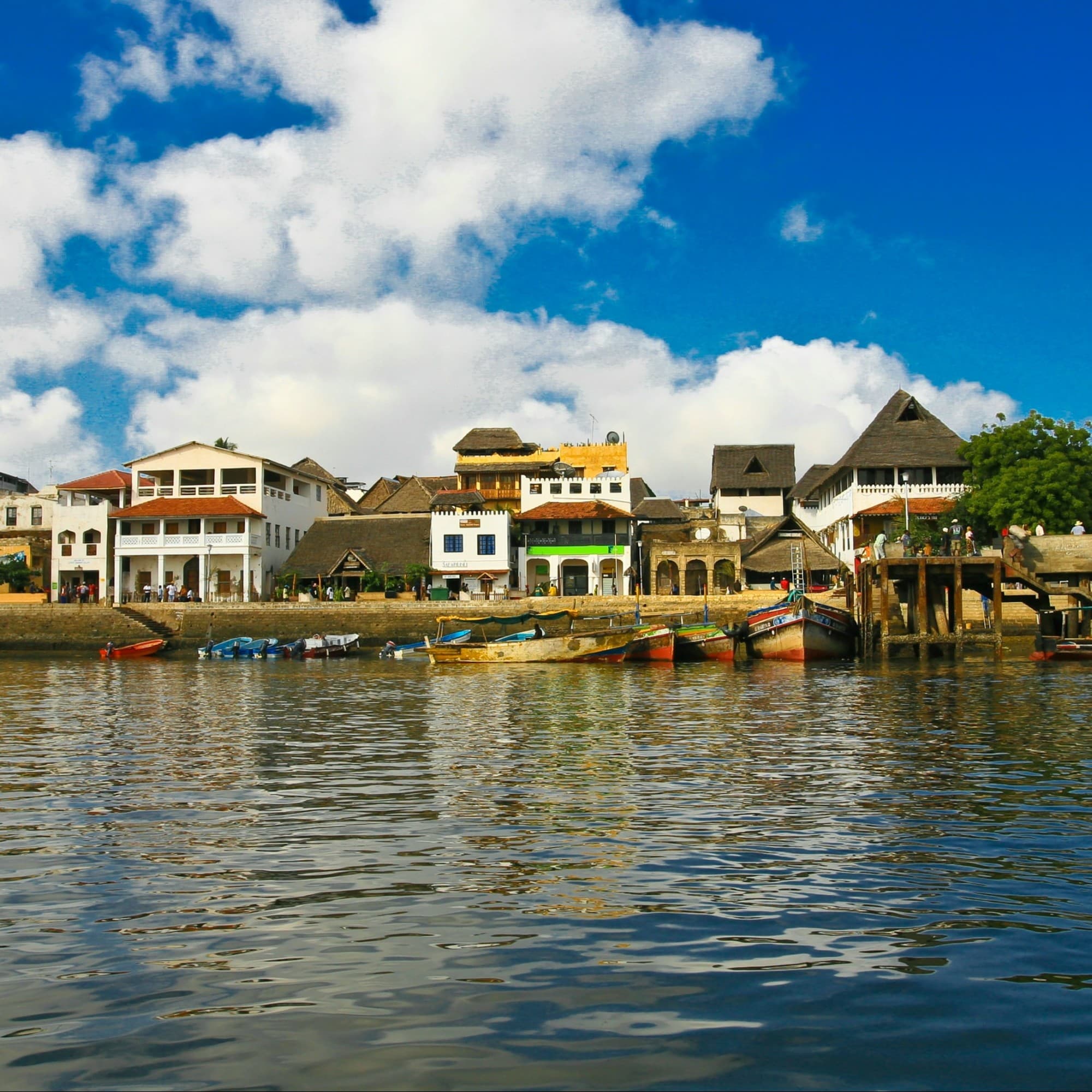 A row of quaint and vibrant houses by a body of water on a sunny day.