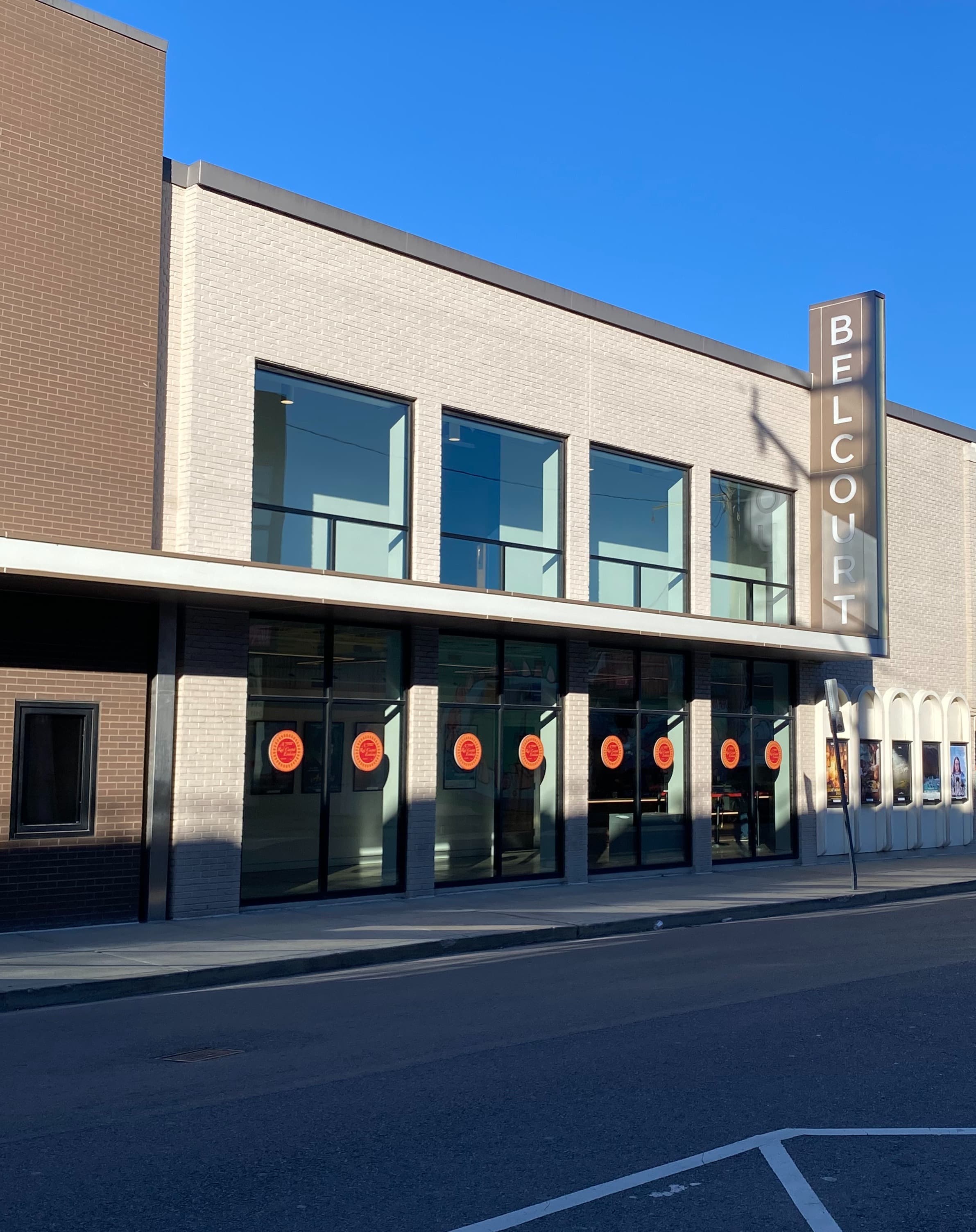 Watch a movie at Belcourt Theatre located in Nashville's Hillsboro Village district. Photo shows a beige brick building with a large Belcourt marquee out front and red stickers on the windows.