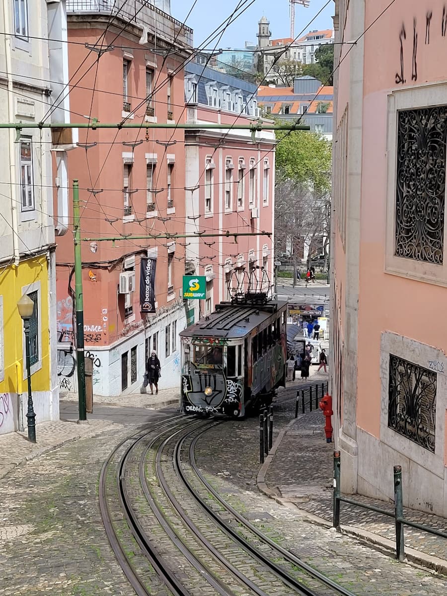 An old-fashioned train car chugging down the tracks through a residential street in Lisbon, Portugal.