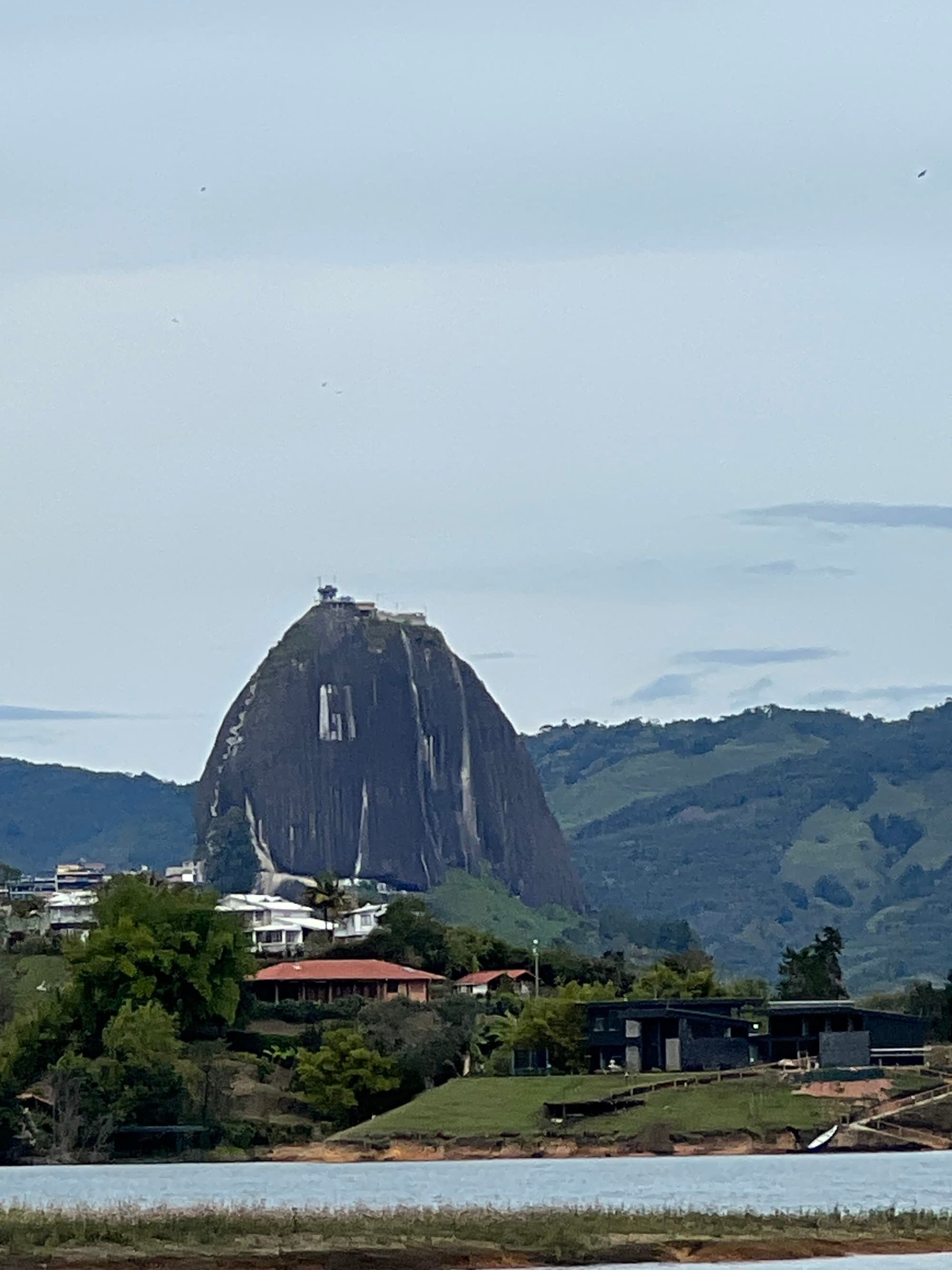 A view of green mountains and a pointed hill with buildings in the foreground.