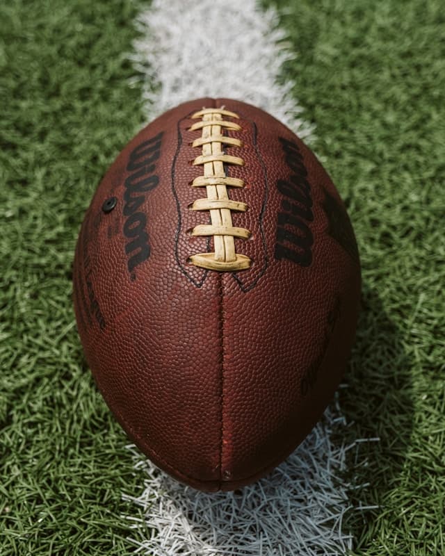 A brown football laying on a green field