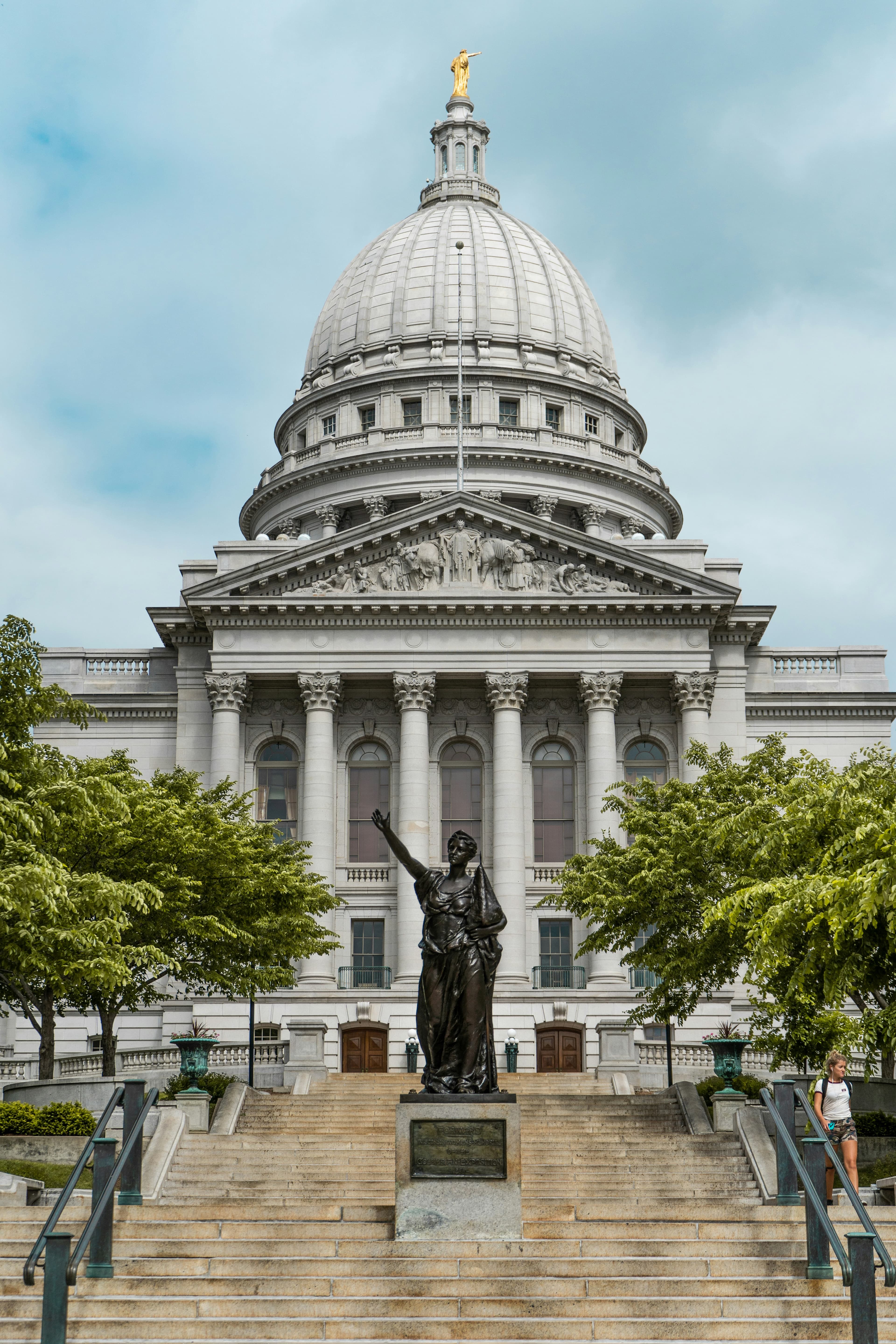 A state building with an arched windows, a statue and steps leading to the entrance.