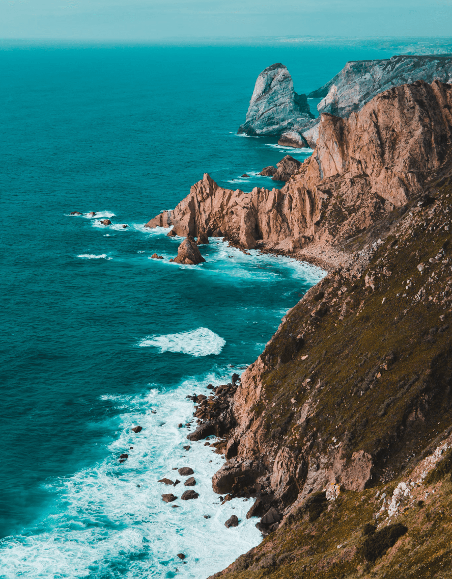 An aerial view of the rocky coastline and vibrant blue sea in Portugal.