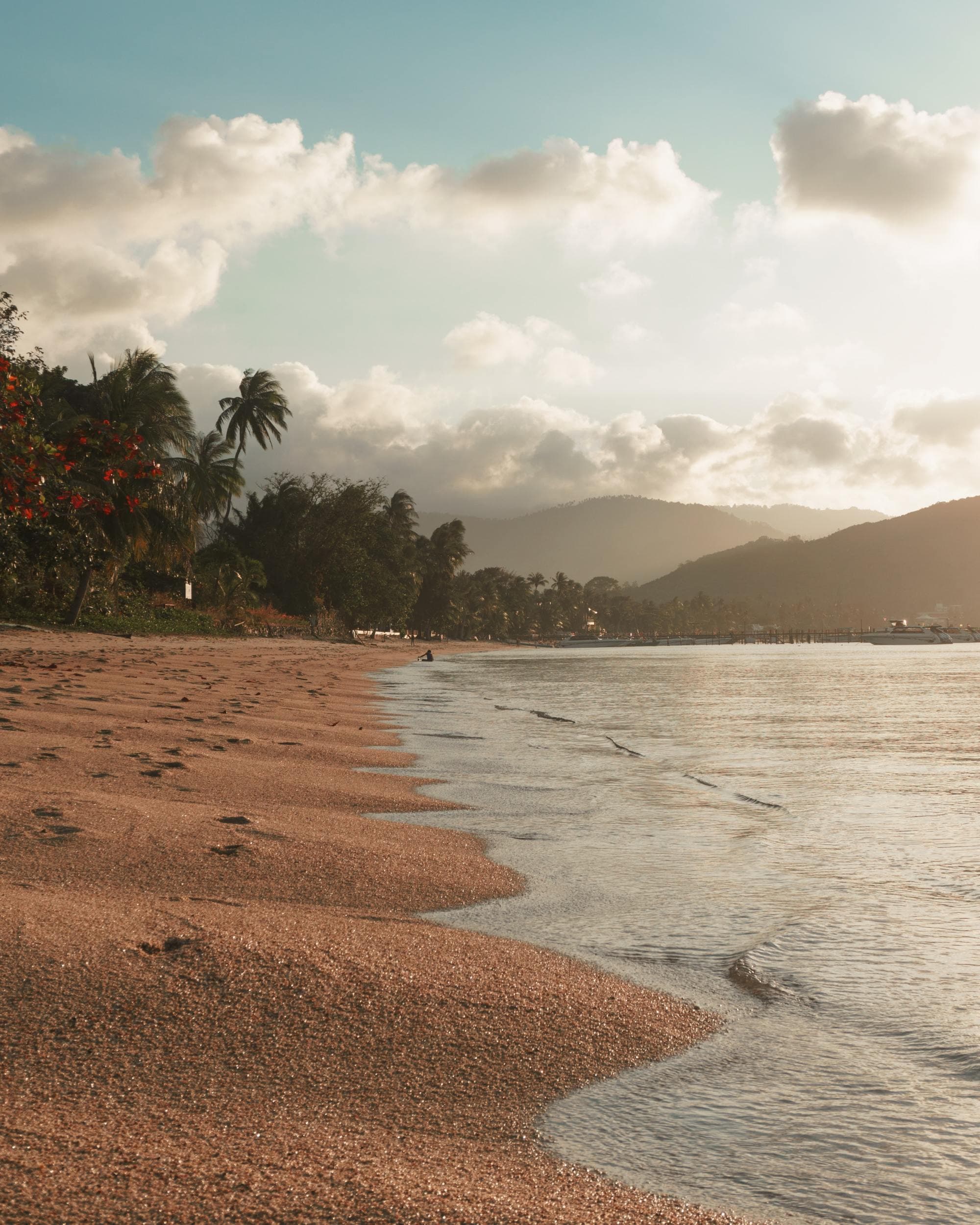 water laps onto an empty tropical beach in the afternoon sun