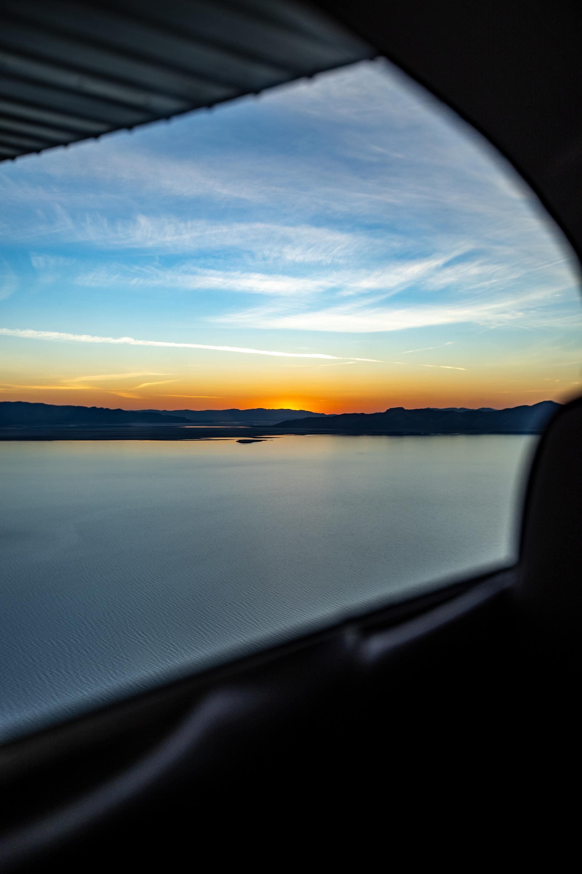 sunset over a pristine lake from the view of a car window