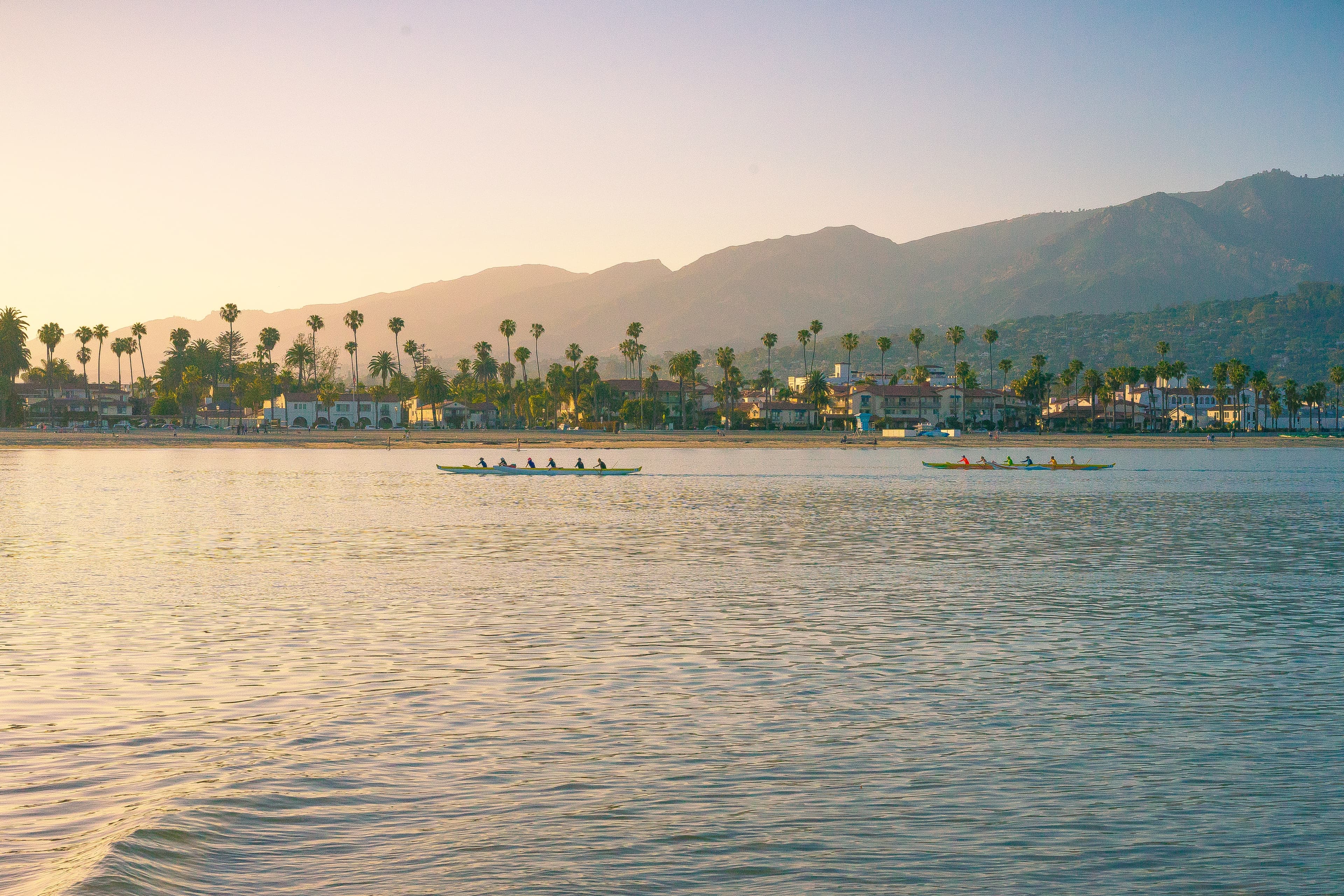 boats in body of water with mountains in the background during sunset