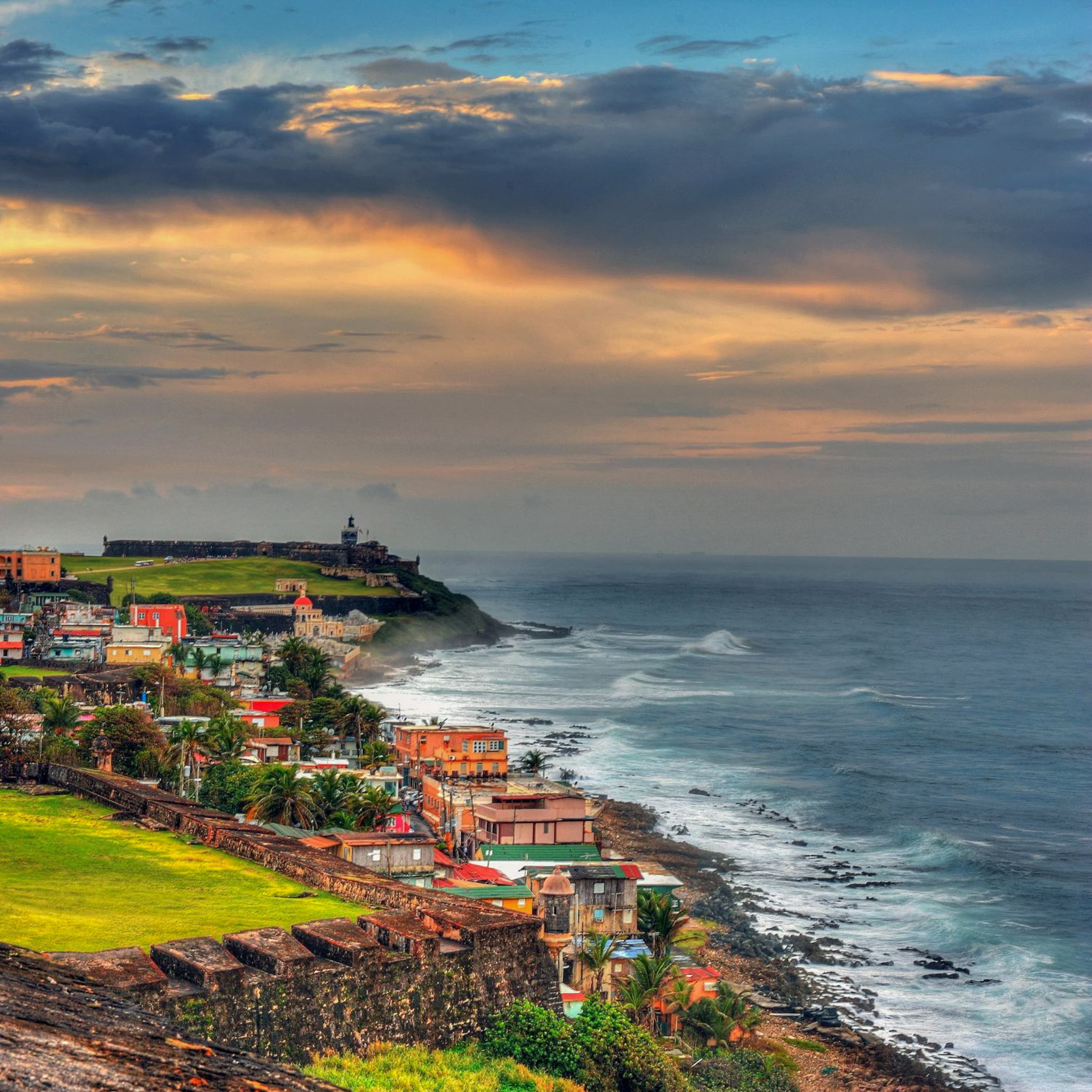 Body of water next to cliff with houses during sunset