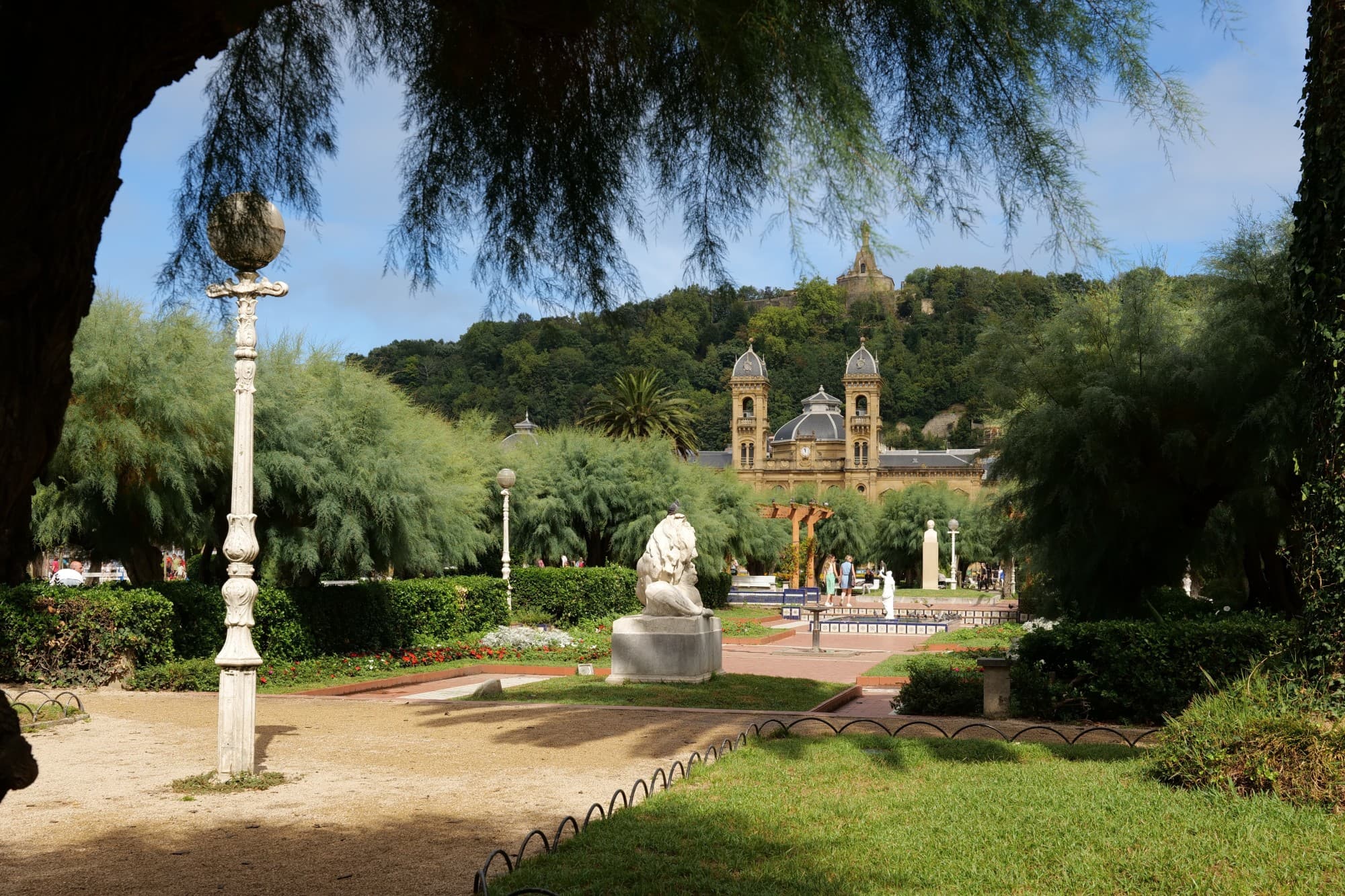 Park with Spanish style church with grass lawns and shade.