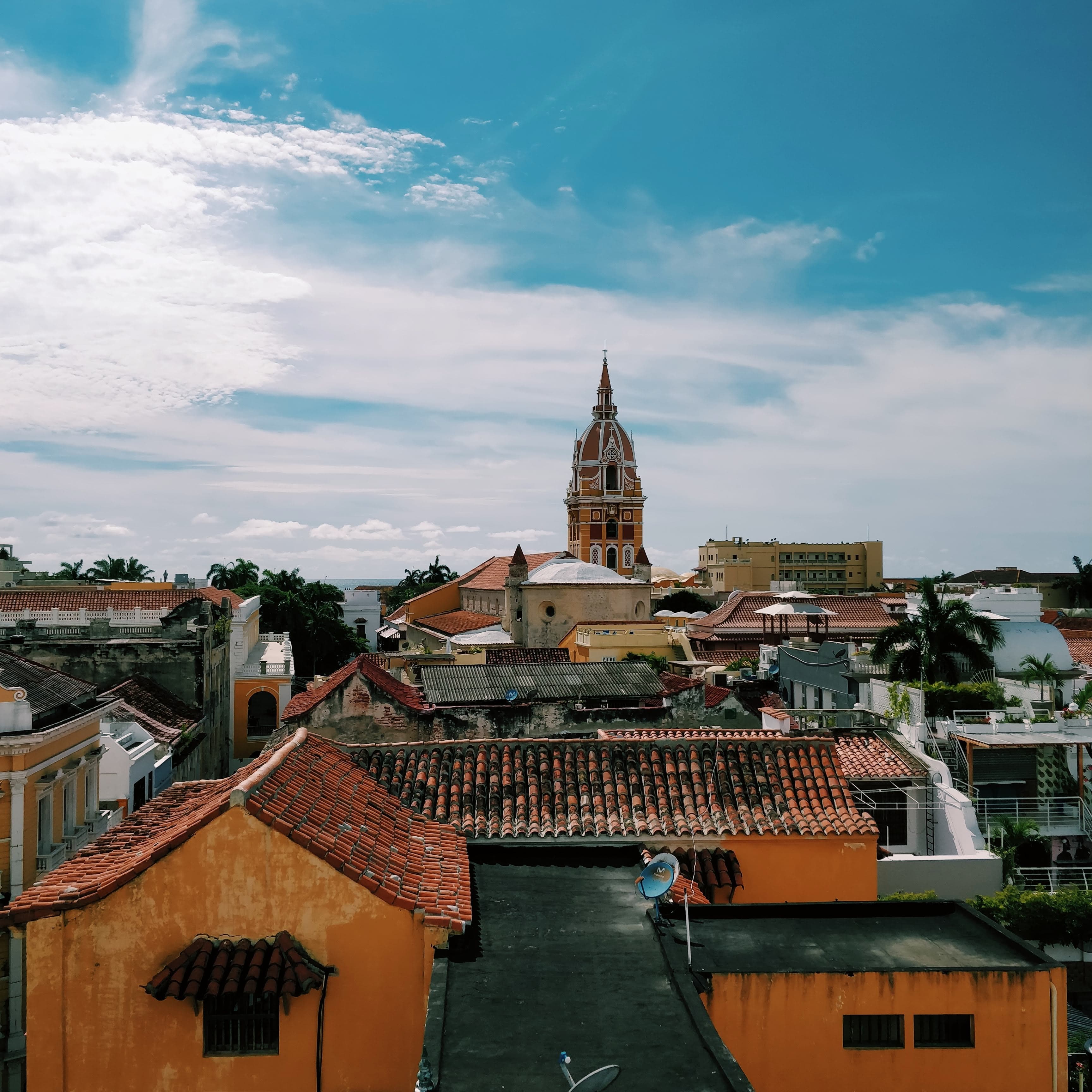 blue skies and white clouds with orange buildings and red roofs city view of Cartagena in Colombia