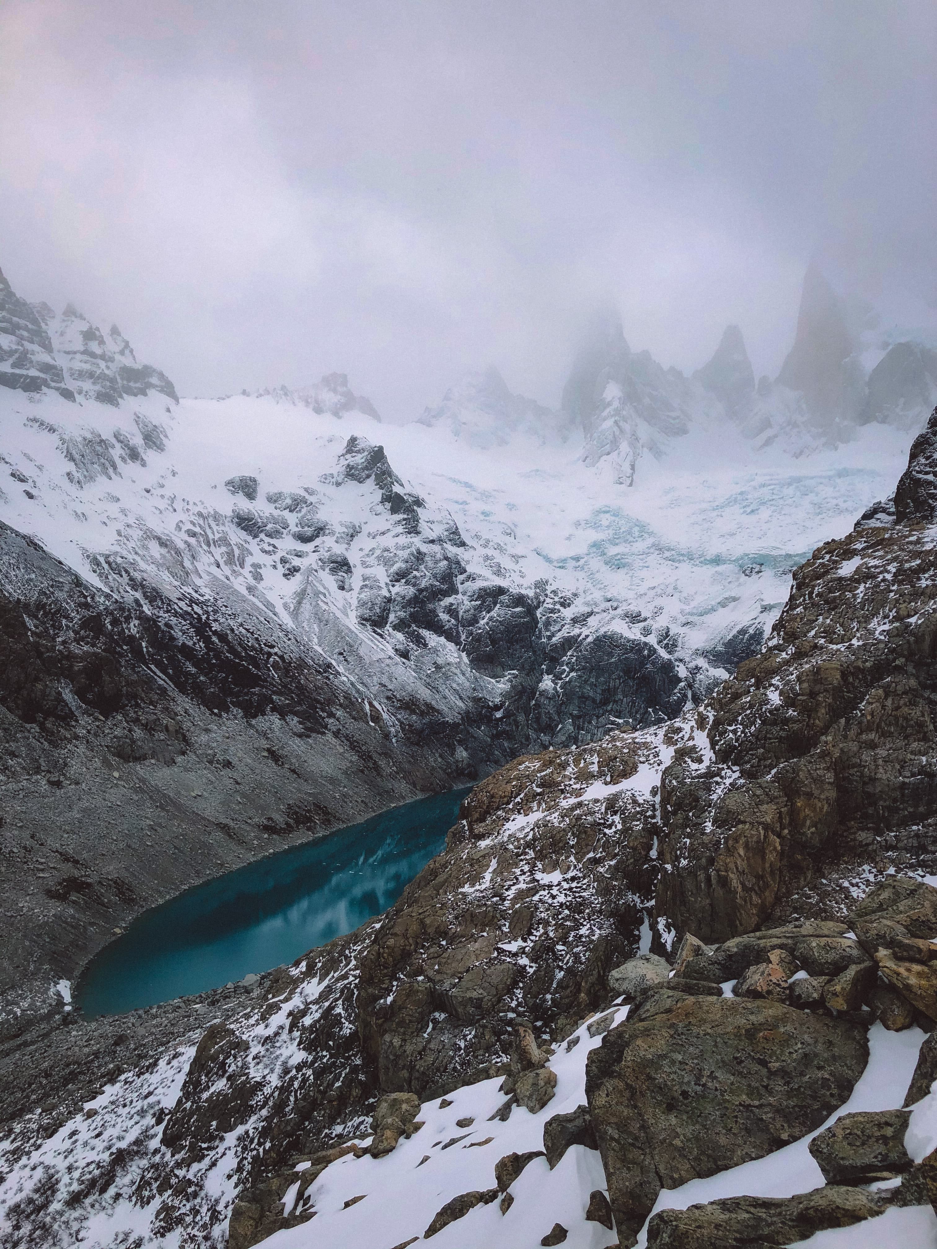 Snow-covered mountains and blue water on a cloudy day