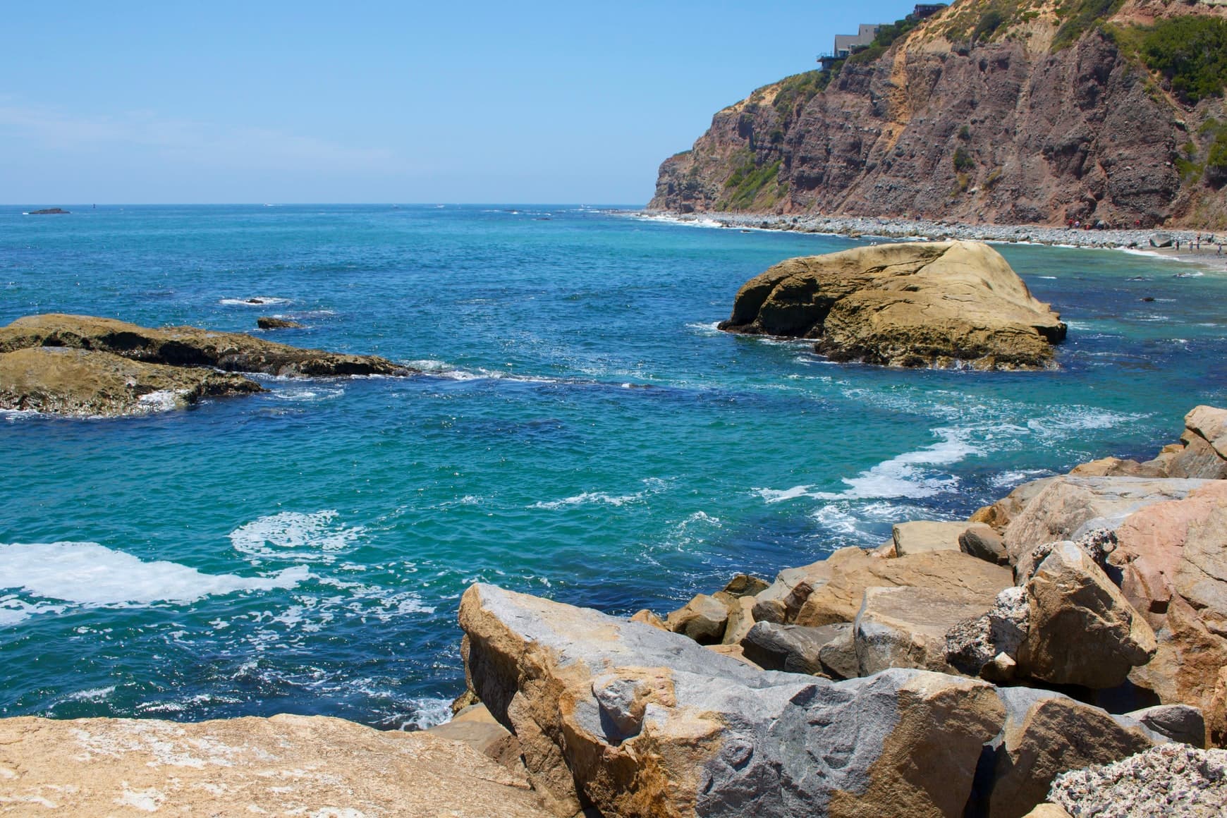 Blue ocean with cliffs and green rocks in Dana point California