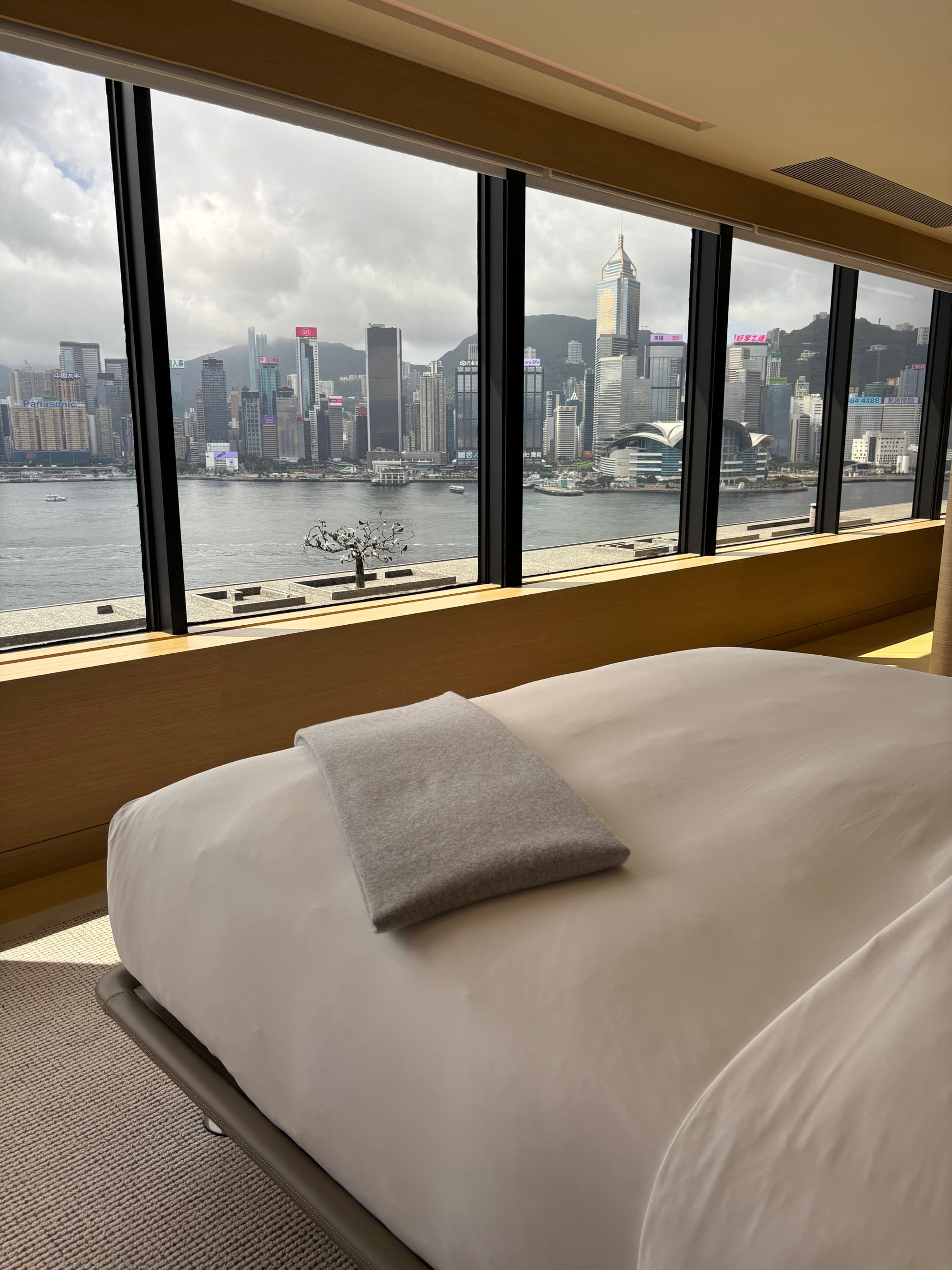 A hotel bedroom with views from the window of a city skyline