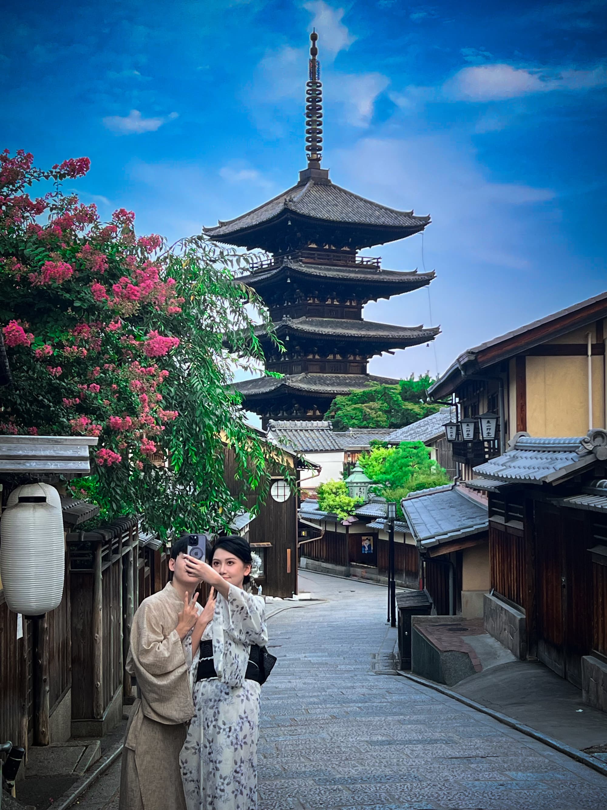 Two people standing on a paved walkway in front of a Japanese pagoda.