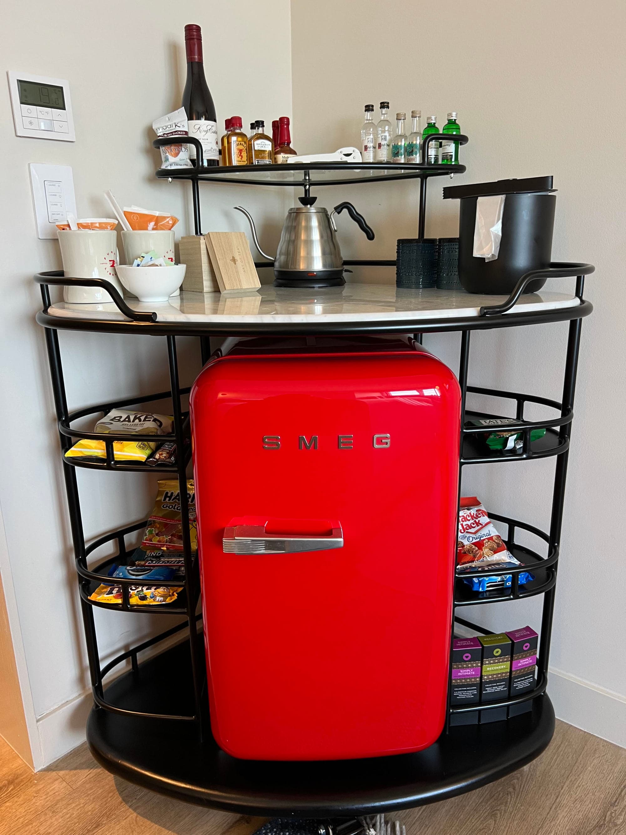 A small red fridge with a coffee bar above it