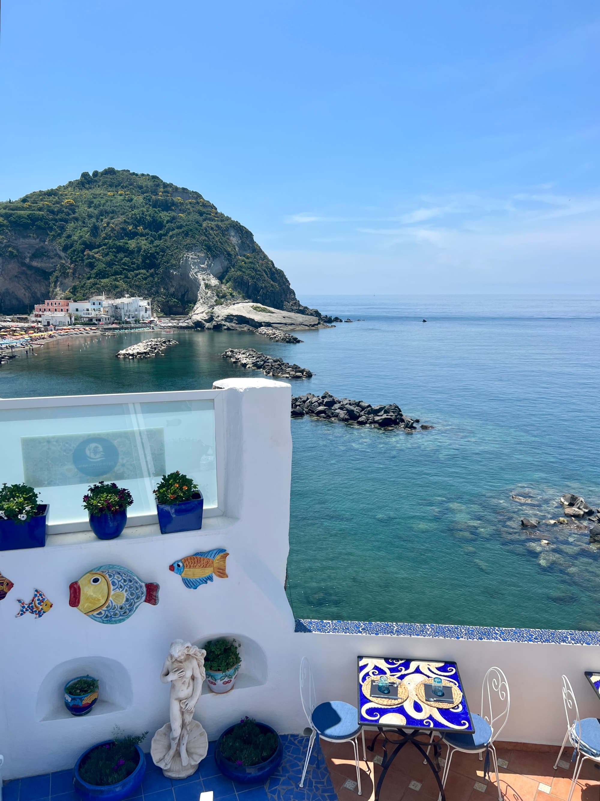 View of a white building next to the sea with a hill in the distance