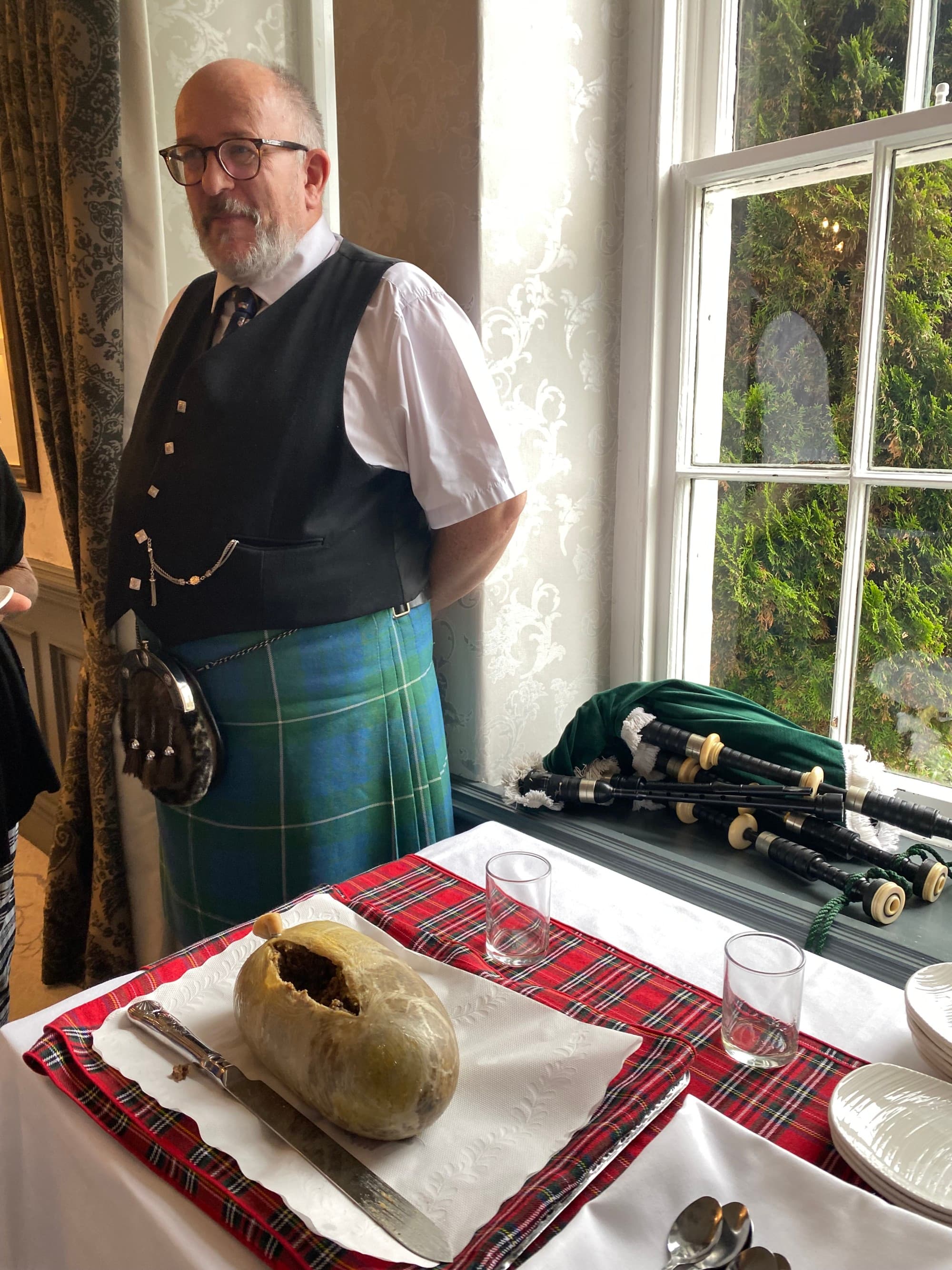 Bagpiper standing next to a haggis sample plate.