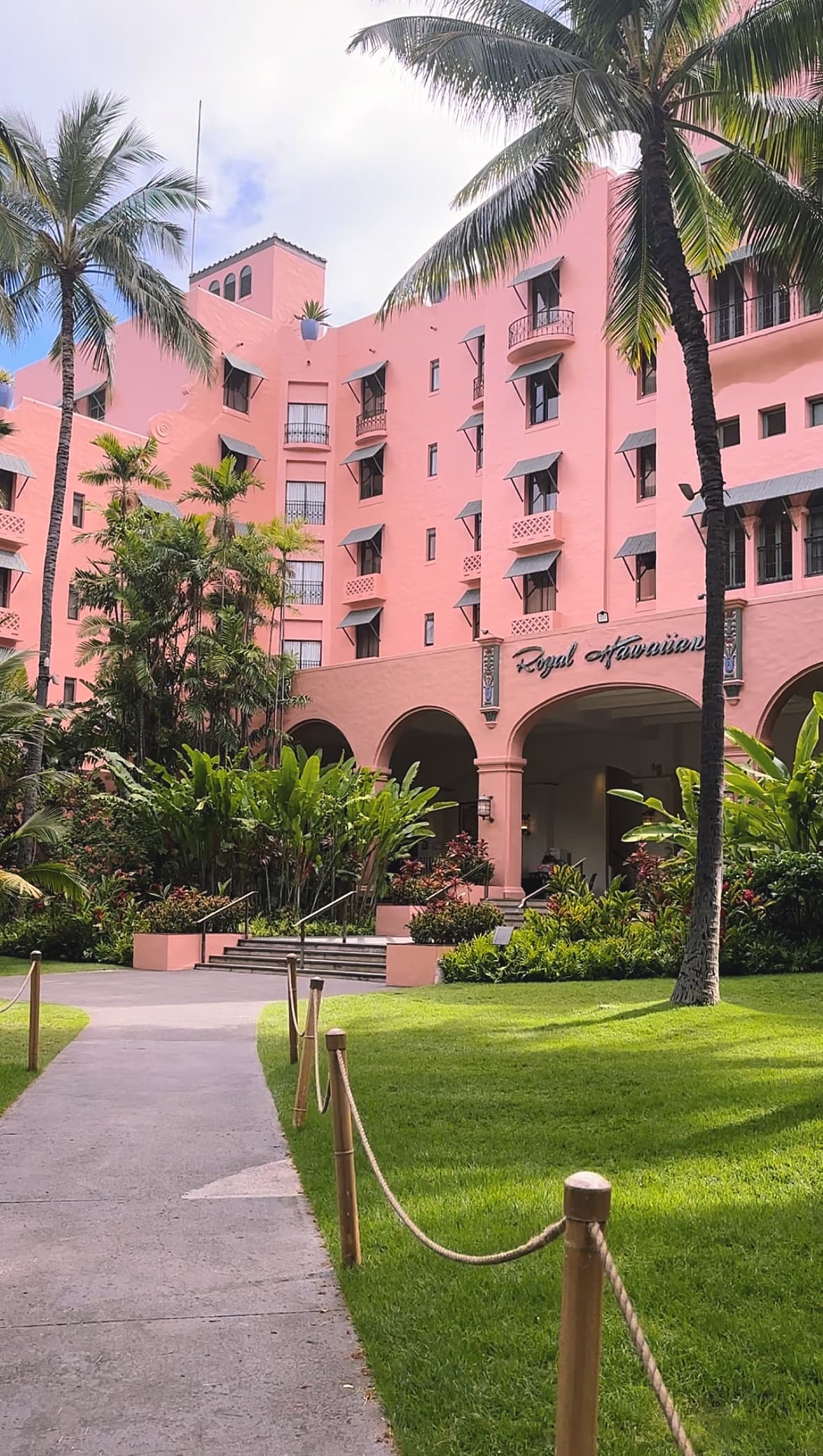 Pink building with green lawns and palm trees.