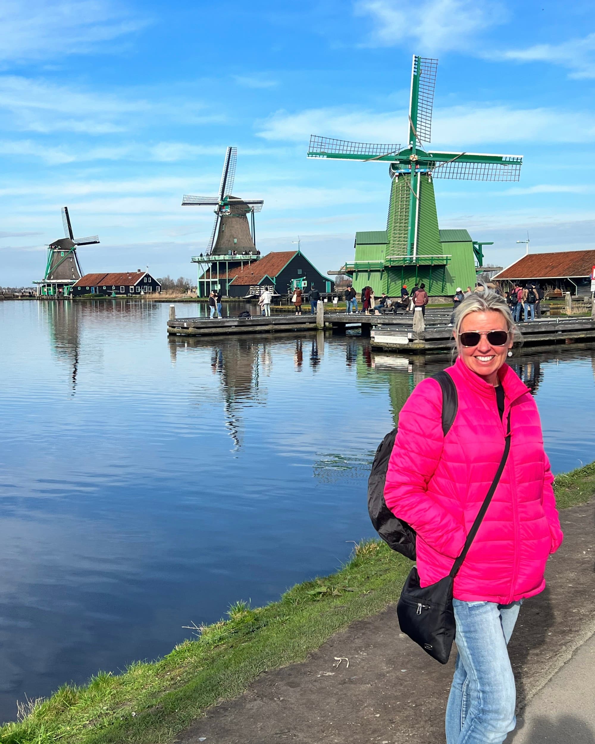 Advisor poses in front of windmills near the shore on a sunny day.