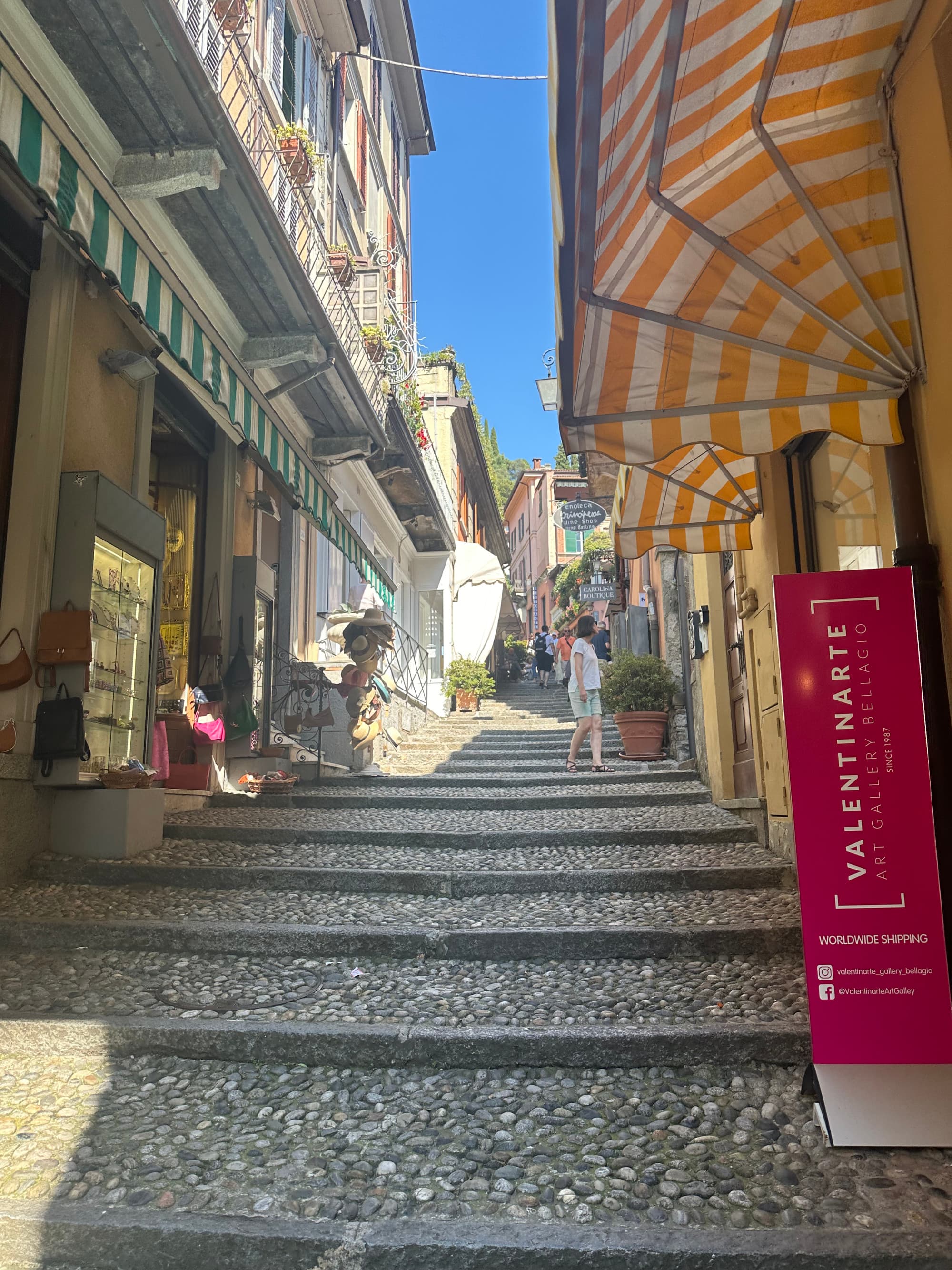 A street view looking down the steps with buildings and shops on either side.  Bellagio - Georgia Goddard