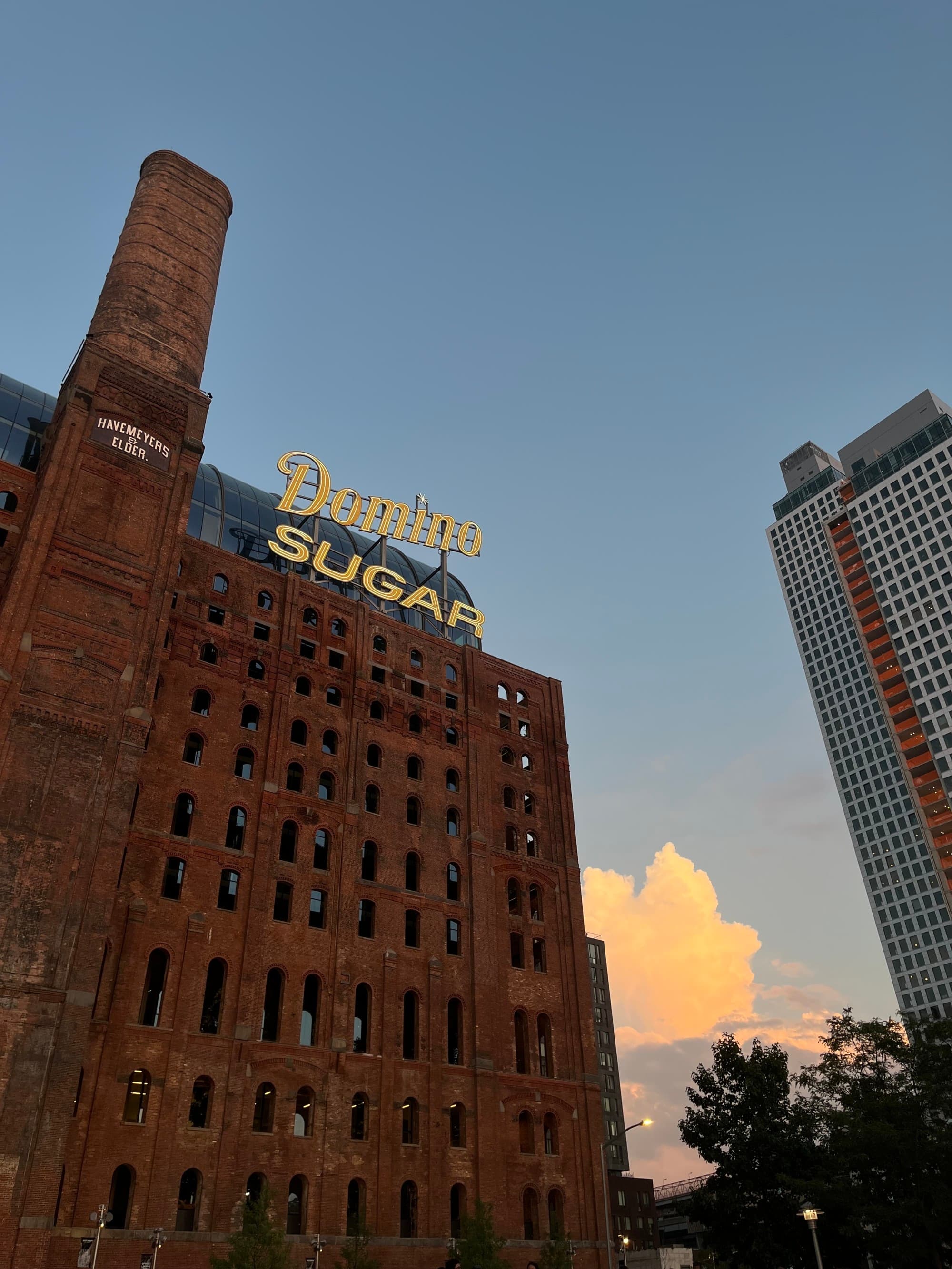 a brick building with a lit sign that reads "Domino Sugar."