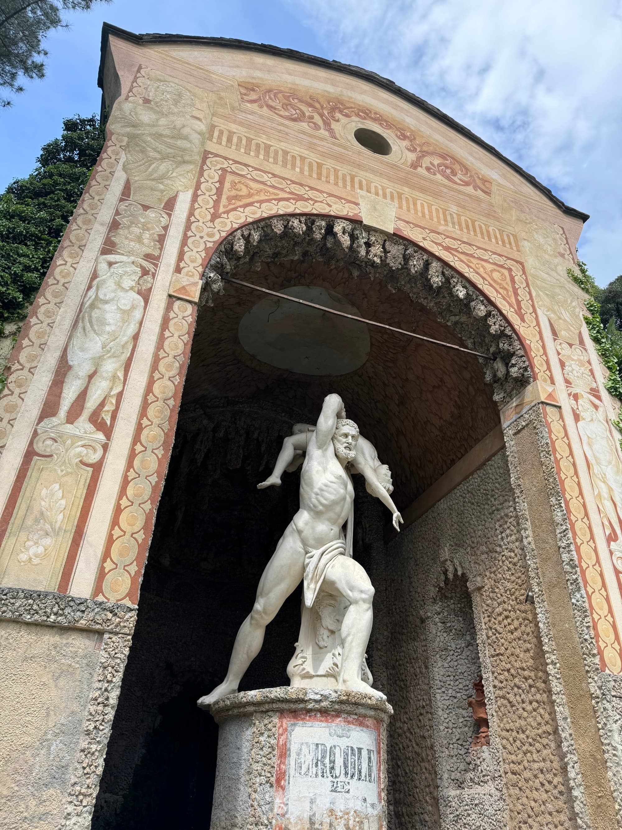 A statue in the hotel garden under an archway reaches to the sky on a sunny day.