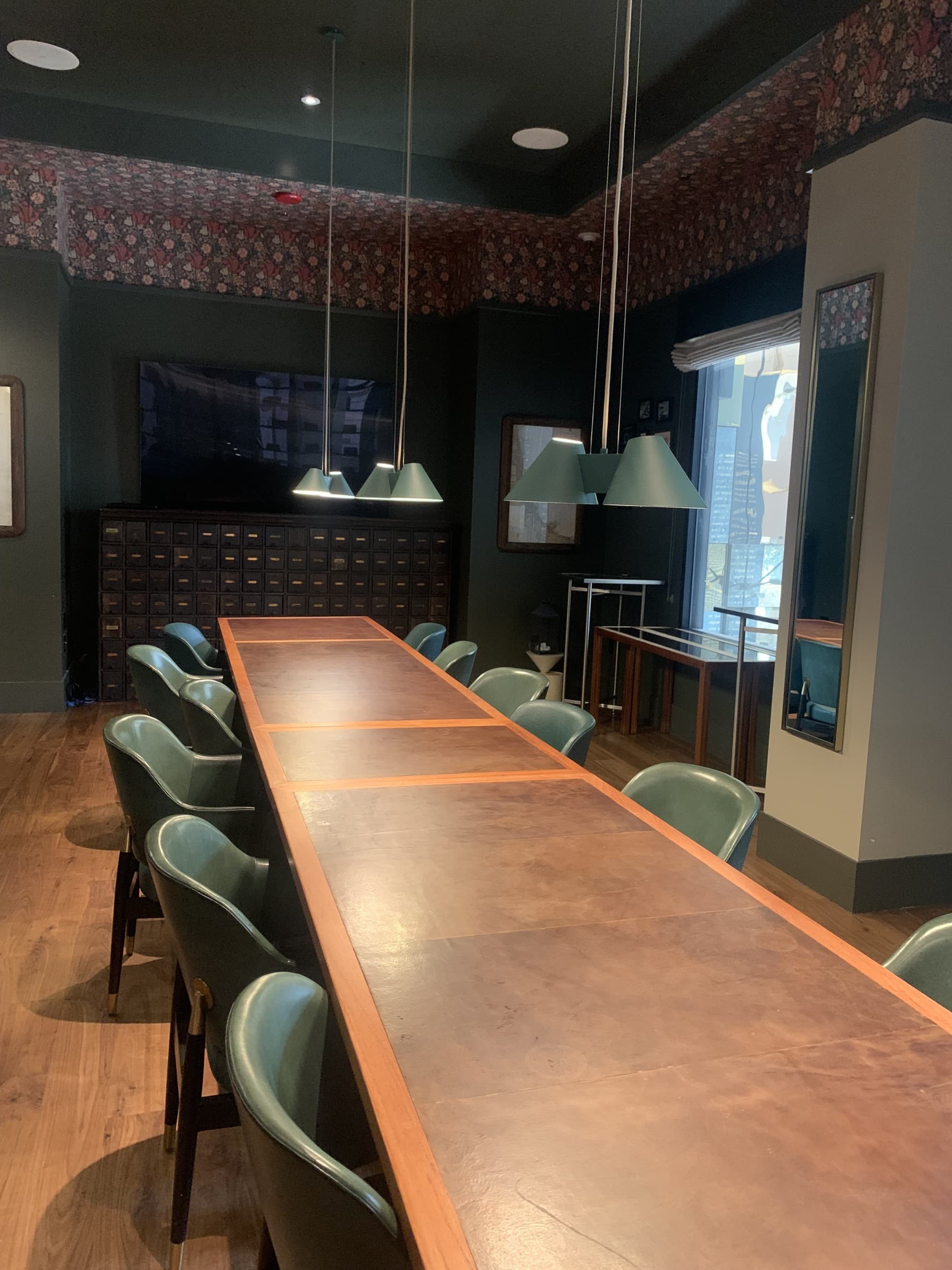 Long meeting room table with chairs and hanging lights.